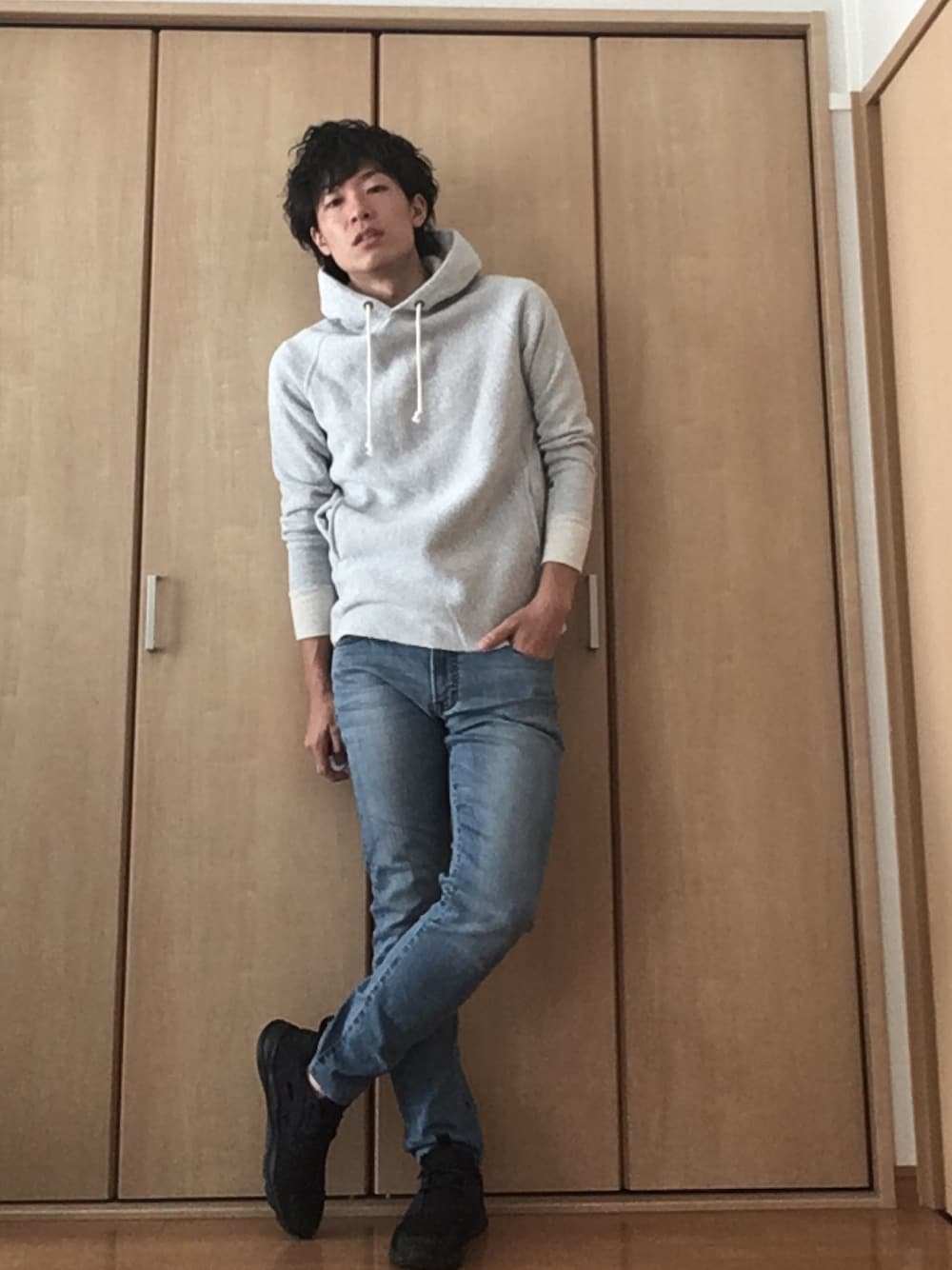 グレー系のパーカー、ブルー系のデニムパンツ、ブラック系のスニーカーを着用したメンズの秋コーディネートの1枚目の写真