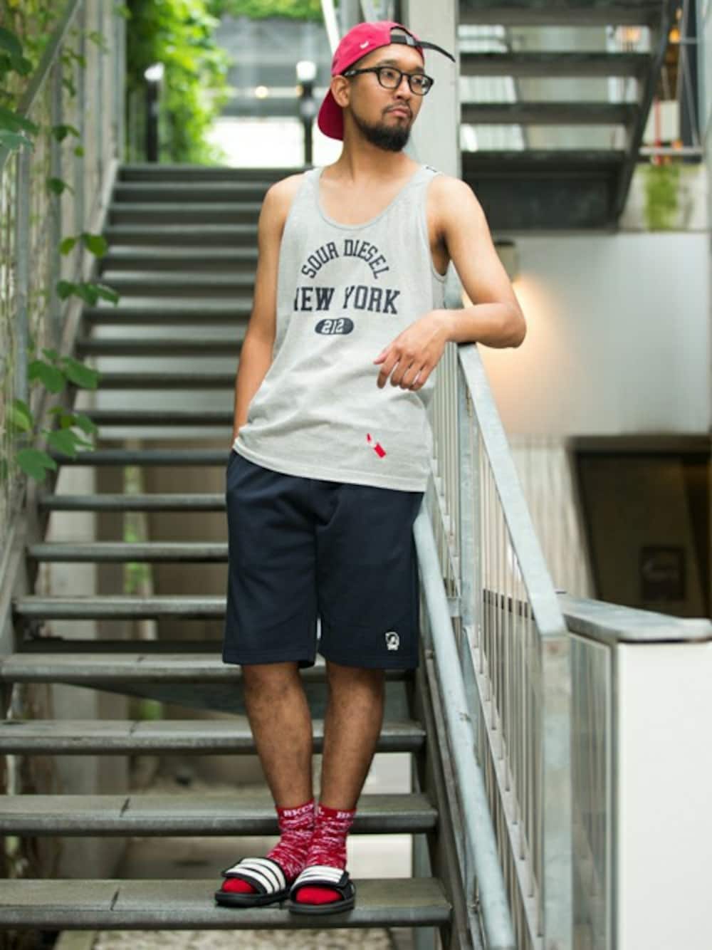 グレー系のタンクトップ、ブルー系のその他パンツ、レッド系のキャップを着用したメンズの夏コーディネートの1枚目の写真