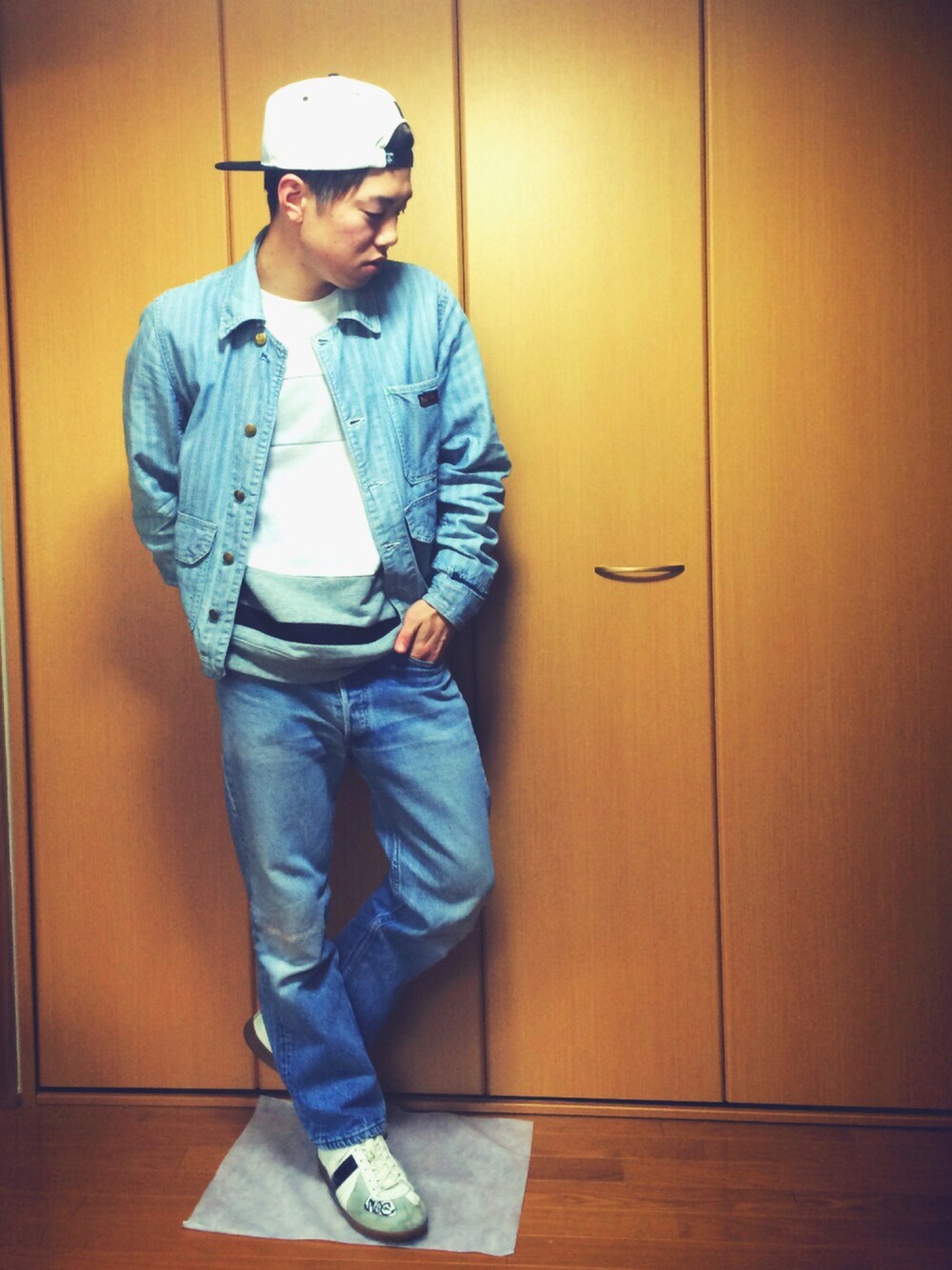 ホワイト系のスウェット、ホワイト系のスニーカー、ブルー系のデニムパンツを着用したメンズの冬コーディネートの1枚目の写真