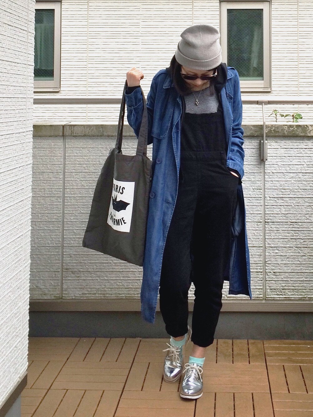 ブラック系のサロペット/オーバーオール、ブラック系のパーカー、ブルー系のトレンチコートを着用したレディースの春コーディネートの1枚目の写真