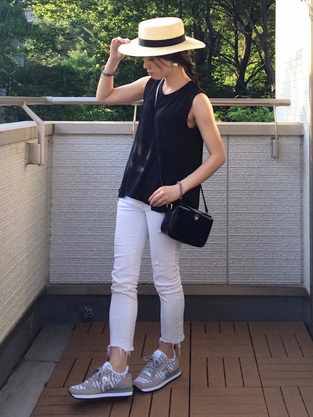 グレー系のスニーカー、ブラック系のTシャツ/カットソー、ホワイト系のデニムパンツを着用したレディースの夏コーディネートの1枚目の写真