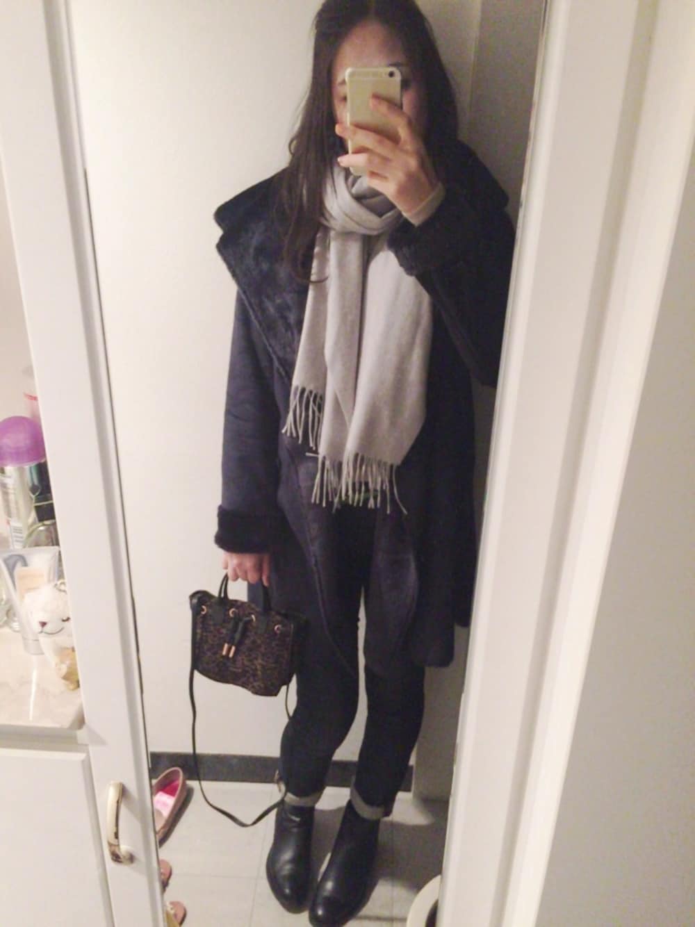 ブラック系のブーツ、ブラウン系のハンドバッグ、ブルー系のデニムパンツを着用したレディースの冬コーディネートの1枚目の写真