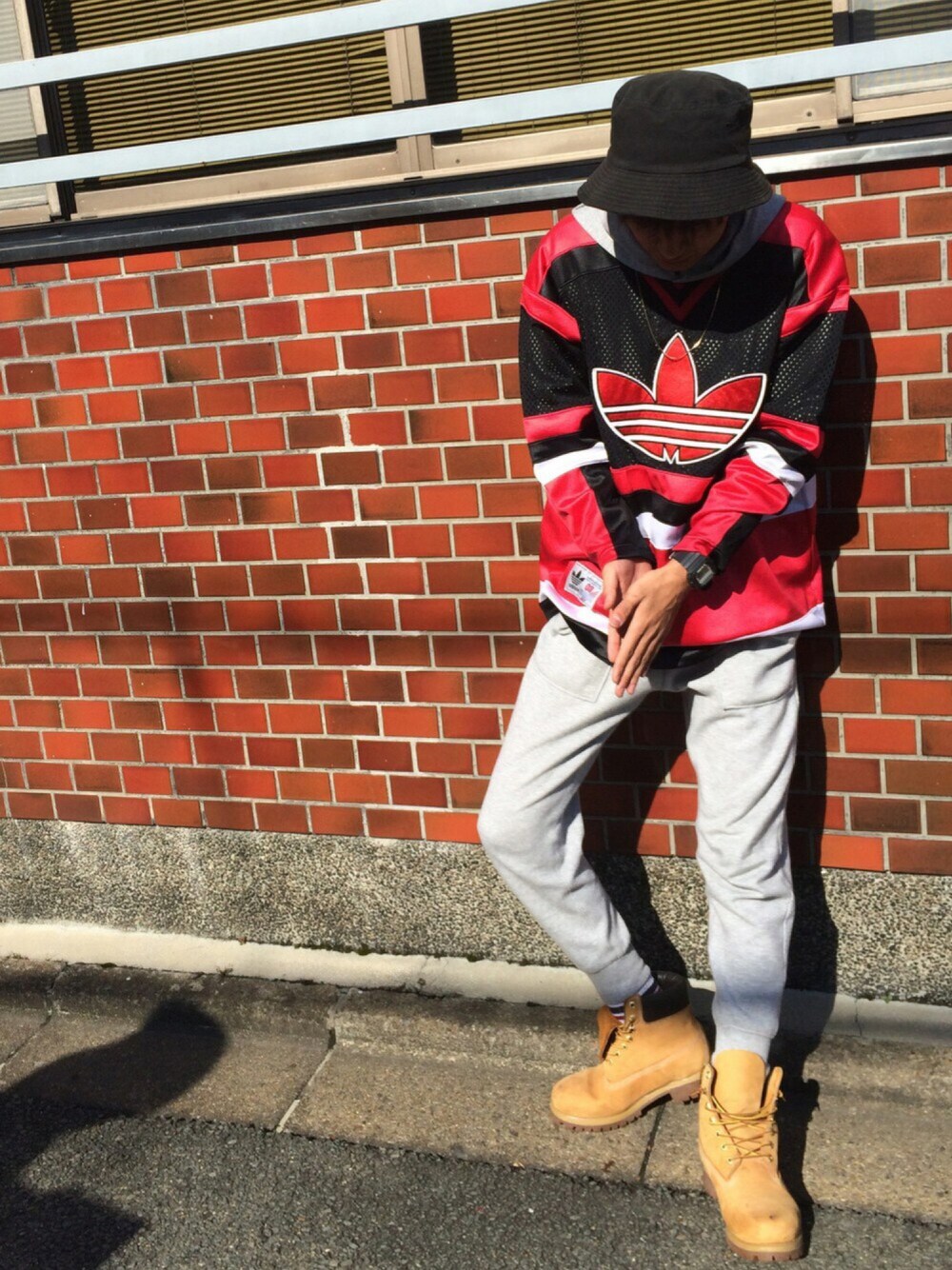 イエロー系のブーツ、グレー系のパンツ、グレー系のパーカーを着用したメンズの秋コーディネートの1枚目の写真