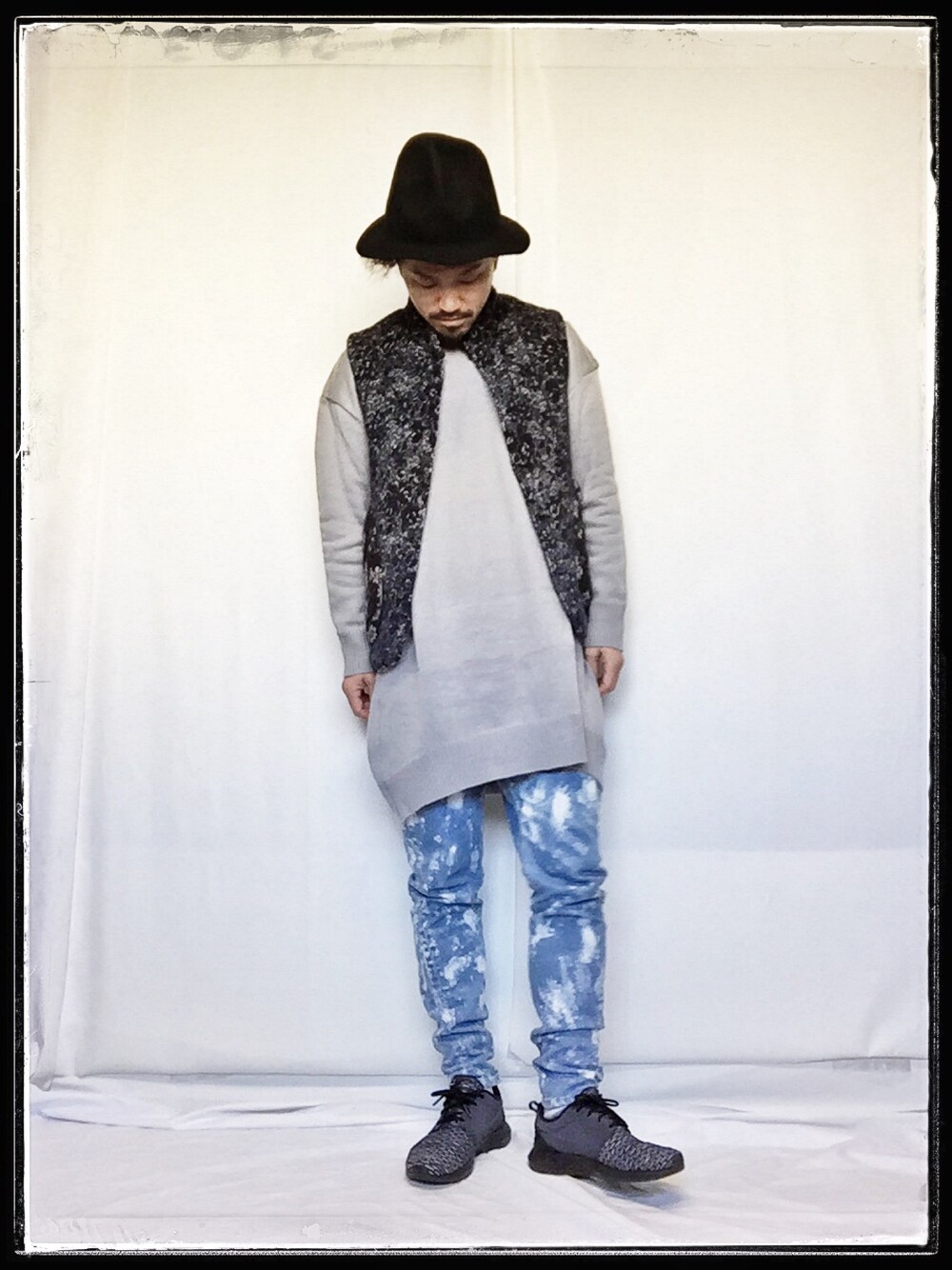 ブラック系のスニーカー、グレー系のニット/セーター、ブルー系のベストを着用したメンズの冬コーディネートの1枚目の写真