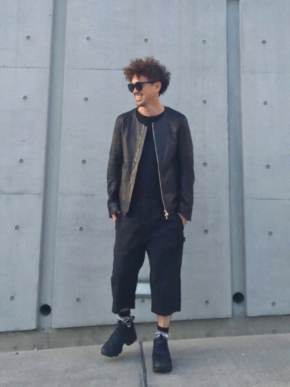 ブラック系のライダースジャケット、ブラック系のスニーカー、ブラック系のつなぎ/オールインワンを着用したメンズの春コーディネートの1枚目の写真