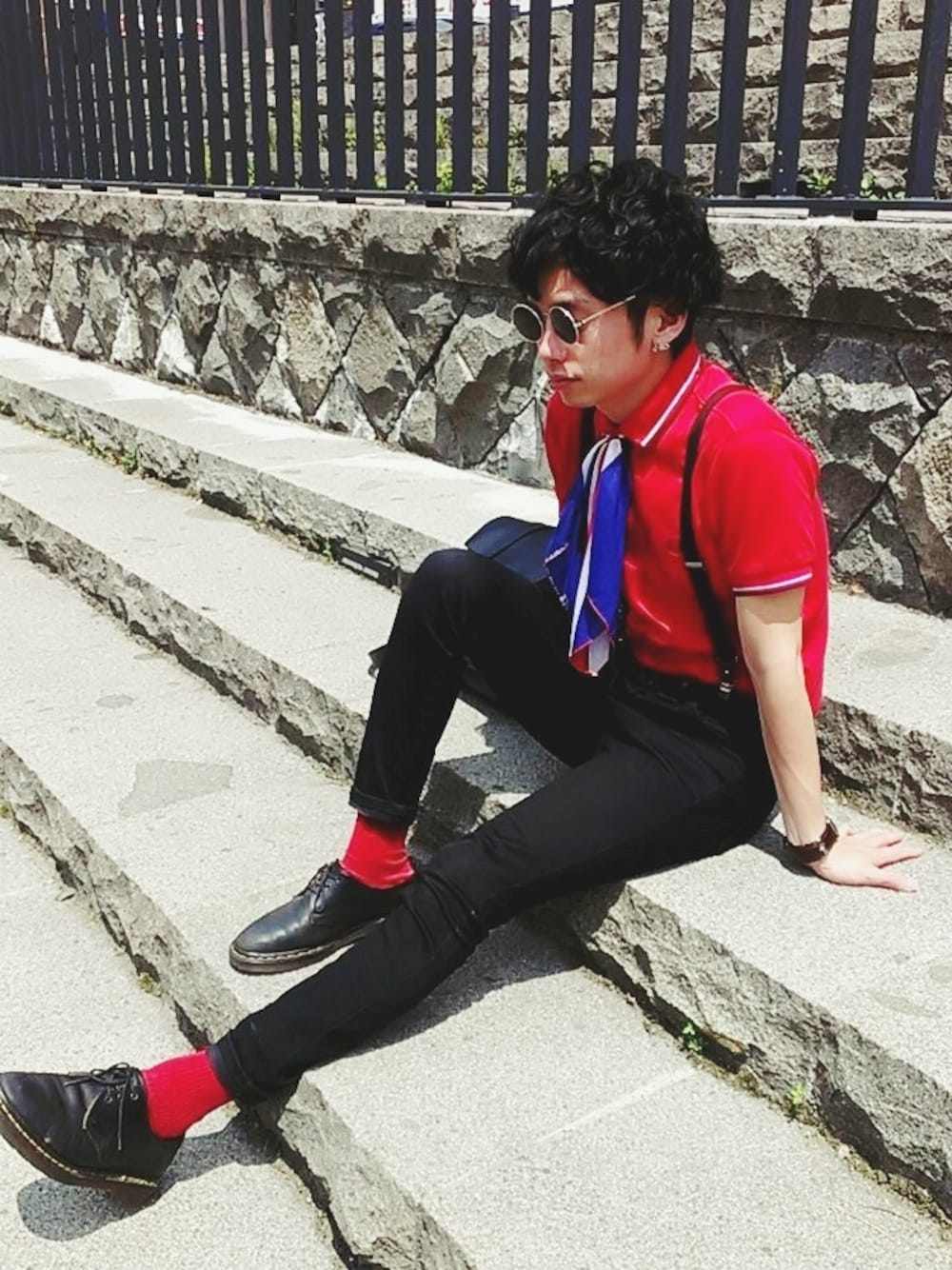 レッド系のポロシャツ、ブラック系のシューズ、ブラック系のその他パンツを着用したメンズの夏コーディネートの1枚目の写真