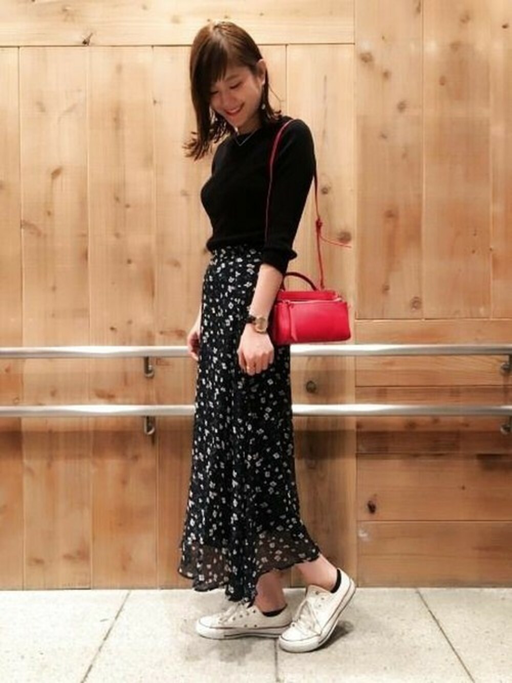 ブラック系のニット/セーター、ブルー系のスカート、レッド系のショルダーバッグを着用したレディースの夏コーディネートの1枚目の写真