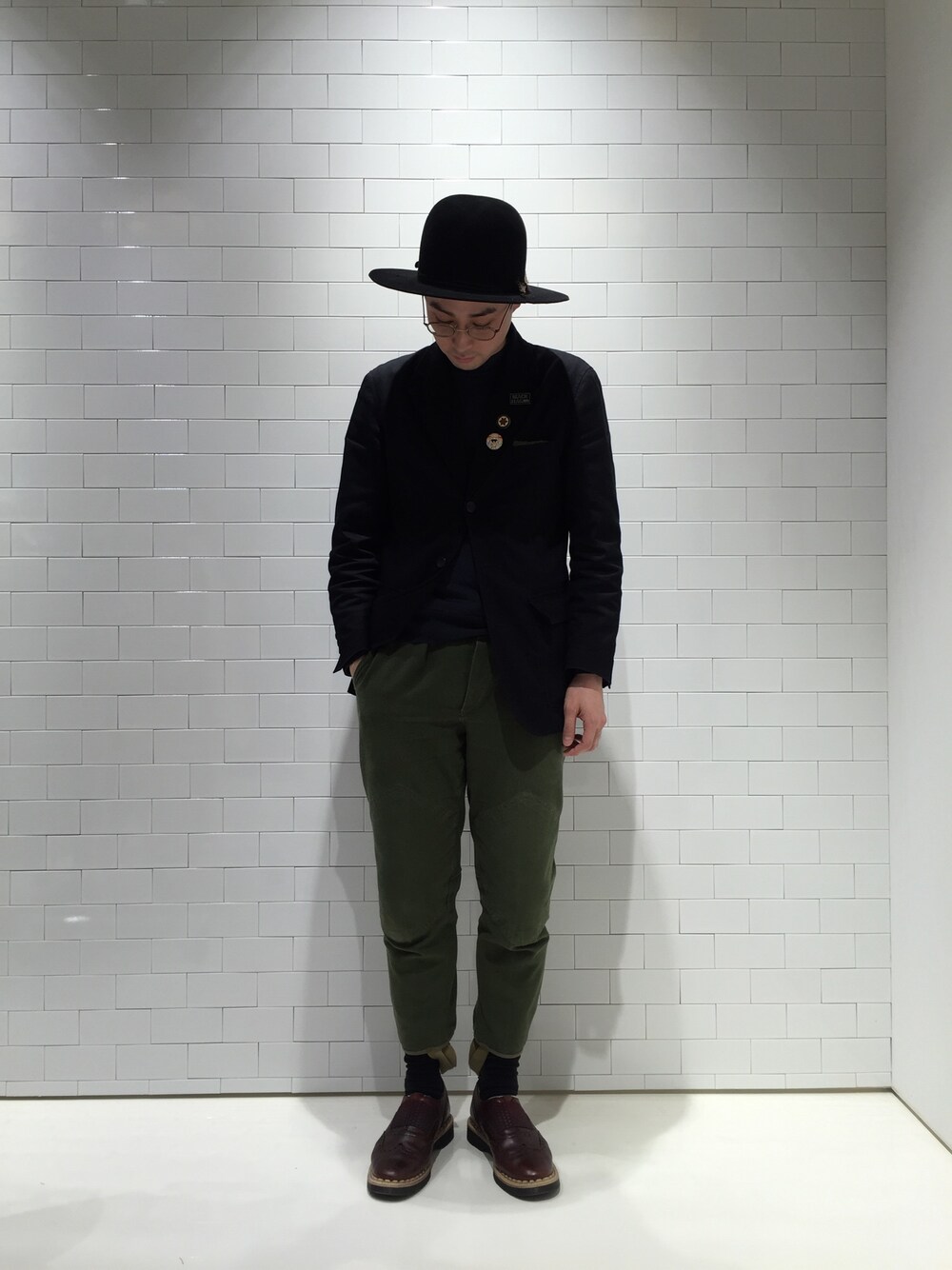 レッド系のドレスシューズ、グリーン系のカーゴパンツ、ブラック系のハットを着用したメンズの冬コーディネートの1枚目の写真