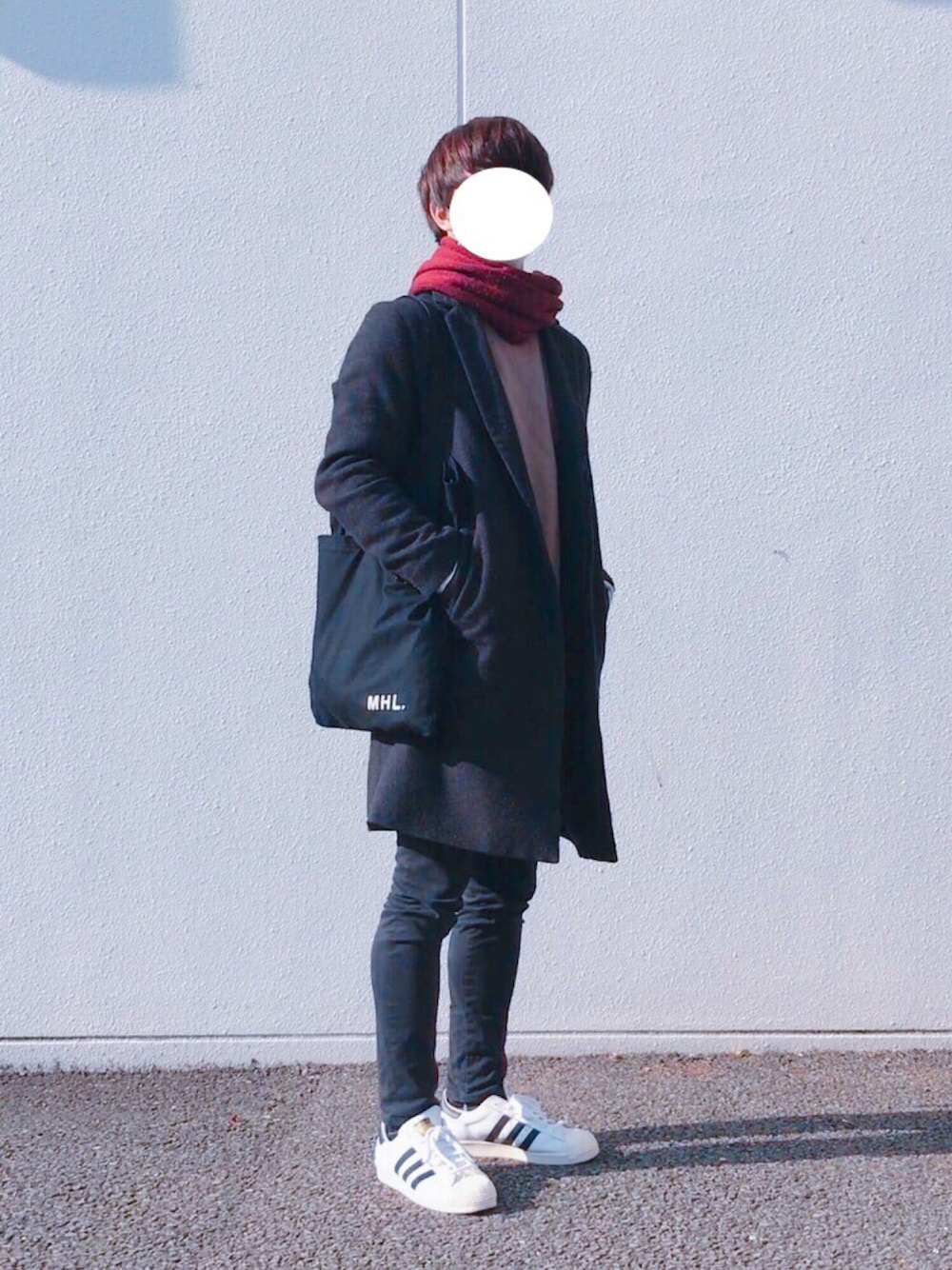 ホワイト系のスニーカー、ブラック系のチノパンツ、ブラック系のトートバッグを着用したメンズの冬コーディネートの1枚目の写真