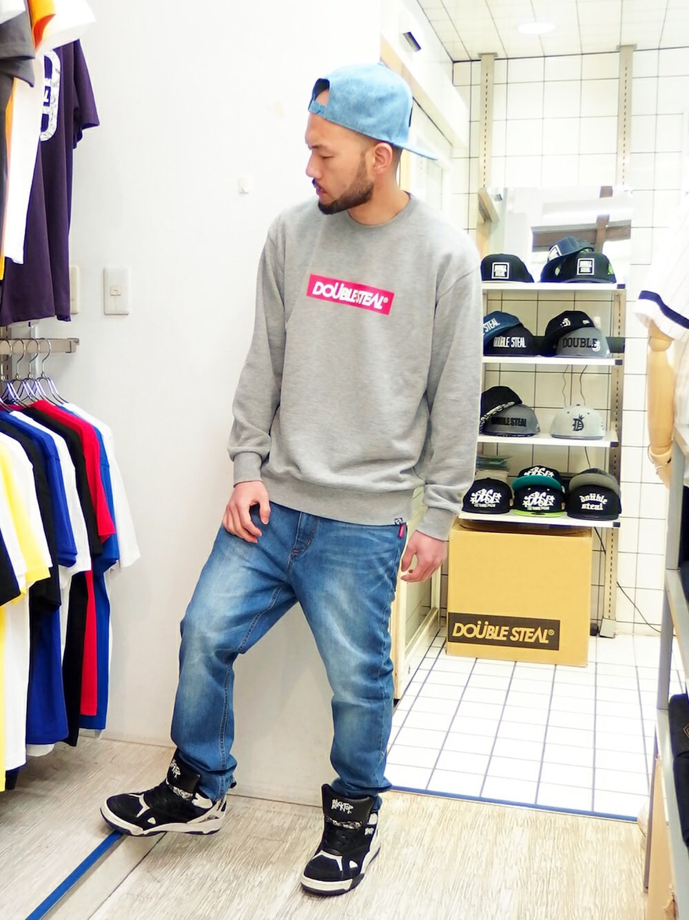 グレー系のスウェット、ブルー系のデニムパンツ、ブラック系のスニーカーを着用したメンズの春コーディネートの1枚目の写真