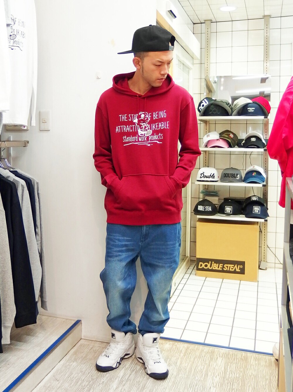レッド系のパーカー、ブルー系のデニムパンツ、ホワイト系のスニーカーを着用したメンズの秋コーディネートの1枚目の写真