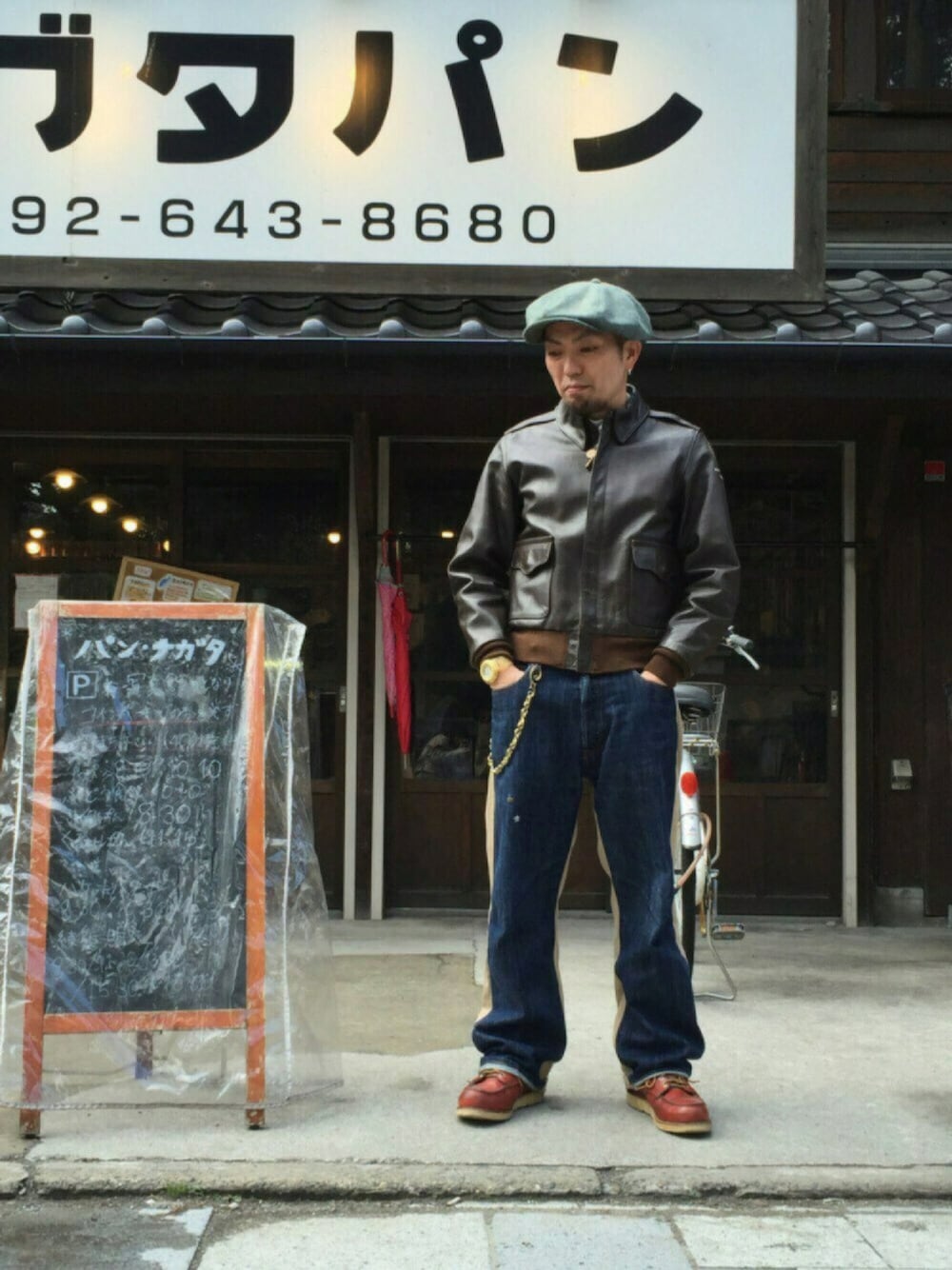 ブラウン系のミリタリージャケット、レッド系のブーツ、グレー系のキャスケットを着用したメンズの冬コーディネートの1枚目の写真