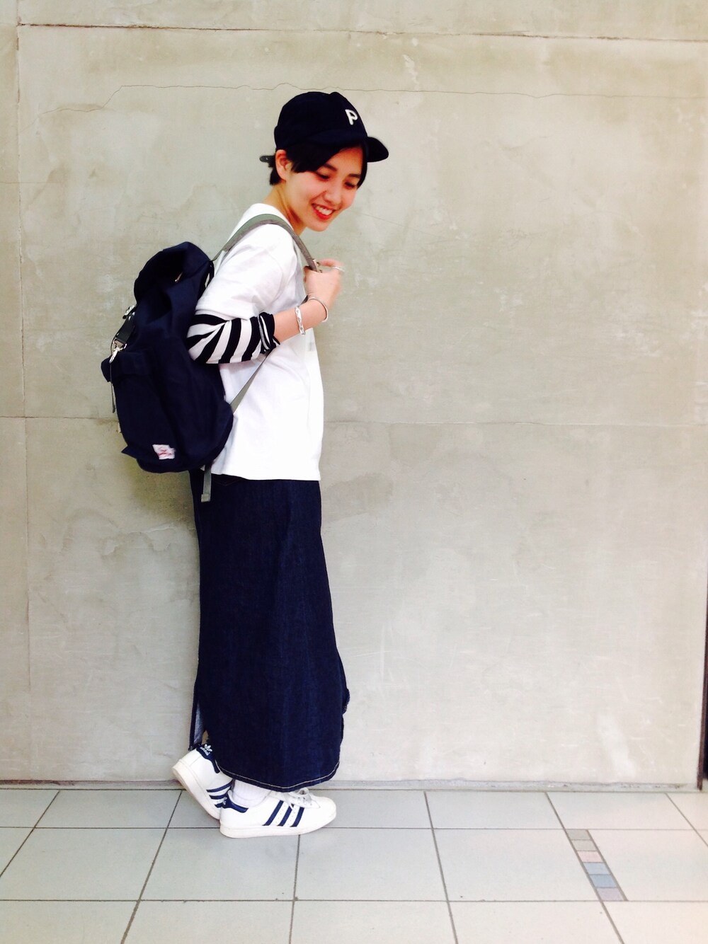 ホワイト系のTシャツ/カットソー、ブルー系のデニムスカート、ホワイト系のスニーカーを着用したレディースの秋コーディネートの1枚目の写真
