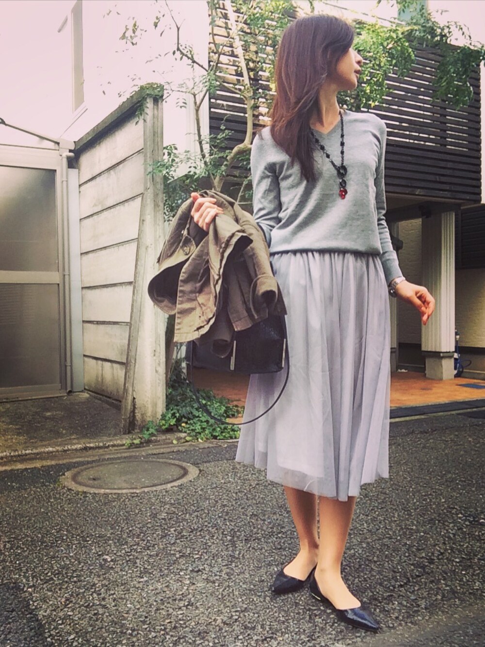 グレー系のニット/セーター、グリーン系のミリタリージャケット、グレー系のスカートを着用したレディースの冬コーディネートの1枚目の写真