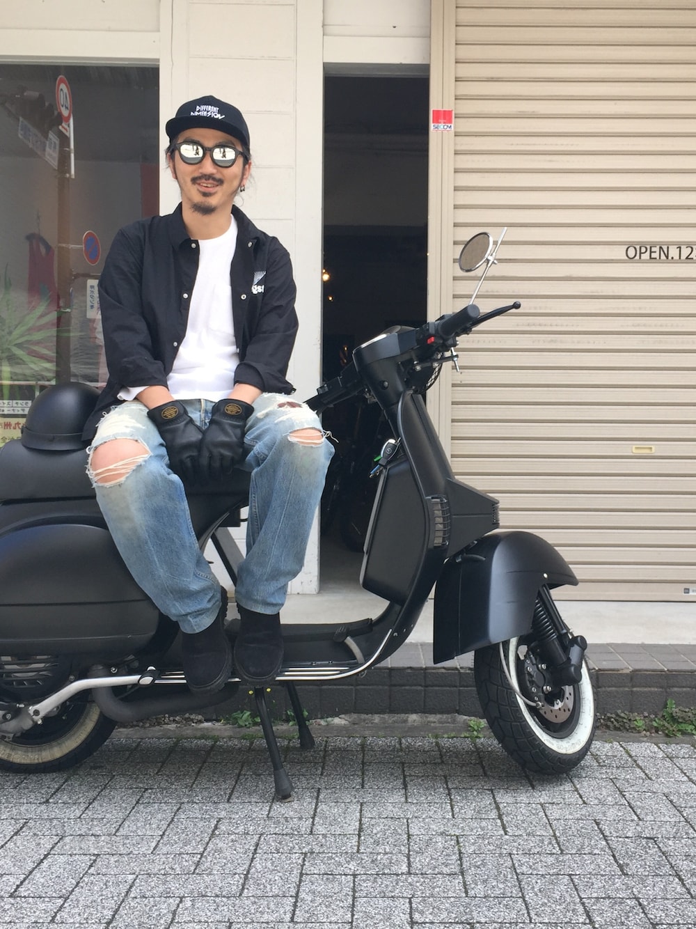 ブルー系のデニムパンツ、ブラック系のTシャツ/カットソー、ブラック系のブーツを着用したメンズの春コーディネートの1枚目の写真