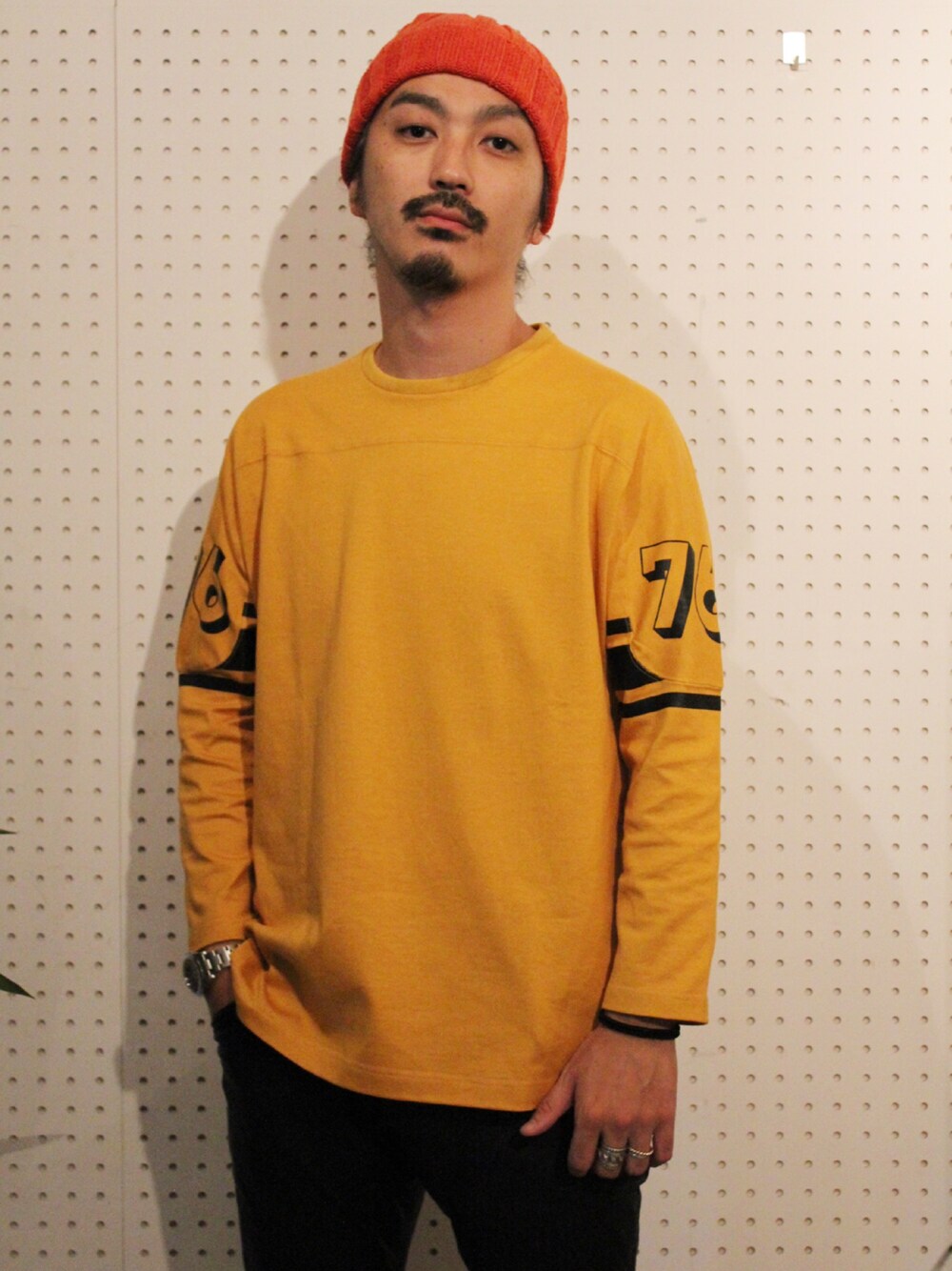 イエロー系のTシャツ/カットソー、オレンジ系のニットキャップ/ビーニーを着用したメンズの秋コーディネートの1枚目の写真