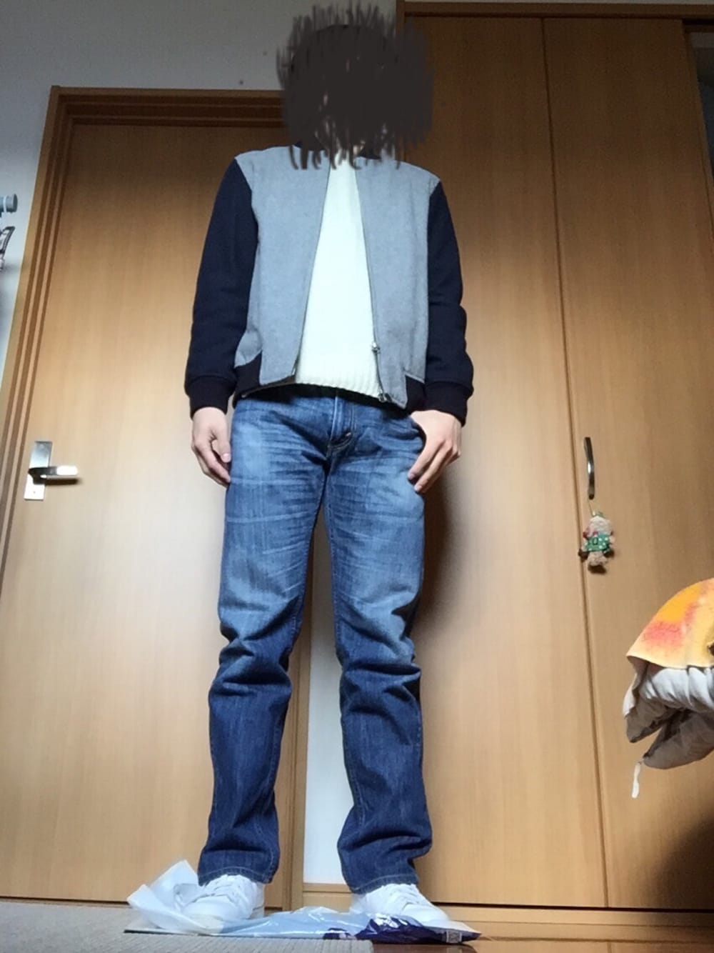 ホワイト系のスニーカー、ブルー系のデニムパンツ、ホワイト系のニット/セーターを着用したメンズの冬コーディネートの1枚目の写真