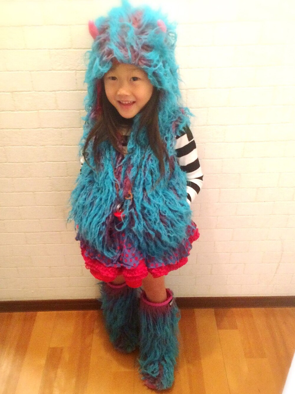 ピンク系のベスト、パープル系のスカート、ピンク系のブーツを着用したキッズの秋コーディネートの1枚目の写真