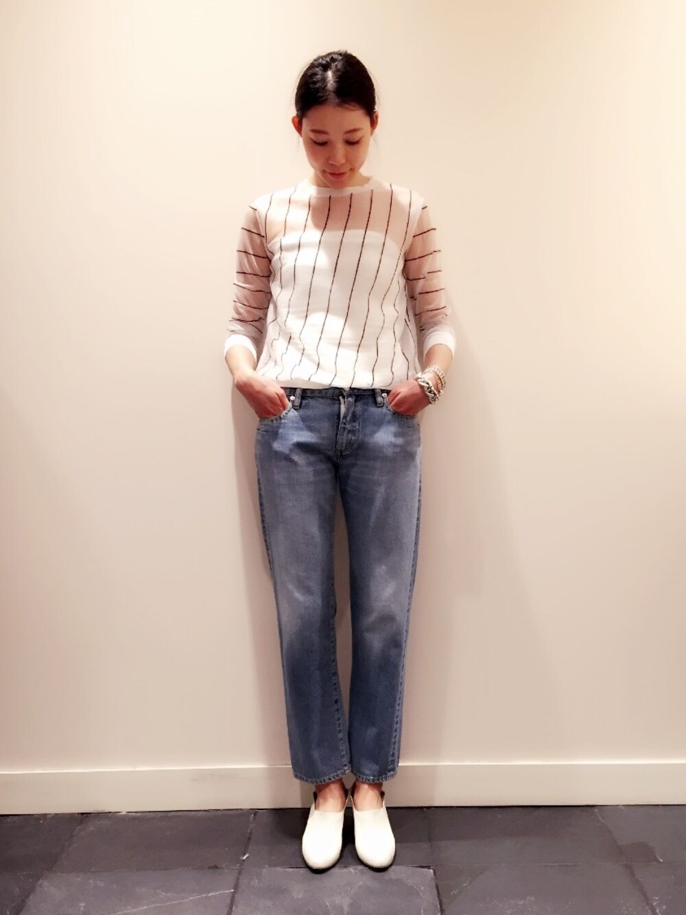 ホワイト系のニット/セーター、ホワイト系のチューブトップ、ブルー系のデニムパンツを着用したレディースの春コーディネートの1枚目の写真
