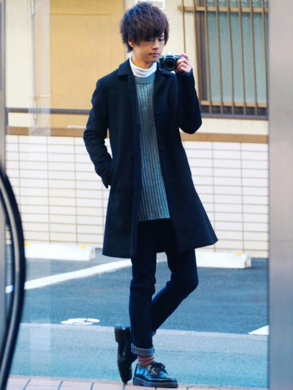 ブラック系のステンカラーコート、ホワイト系のTシャツ/カットソー、グレー系のニット/セーターを着用したメンズの冬コーディネートの1枚目の写真