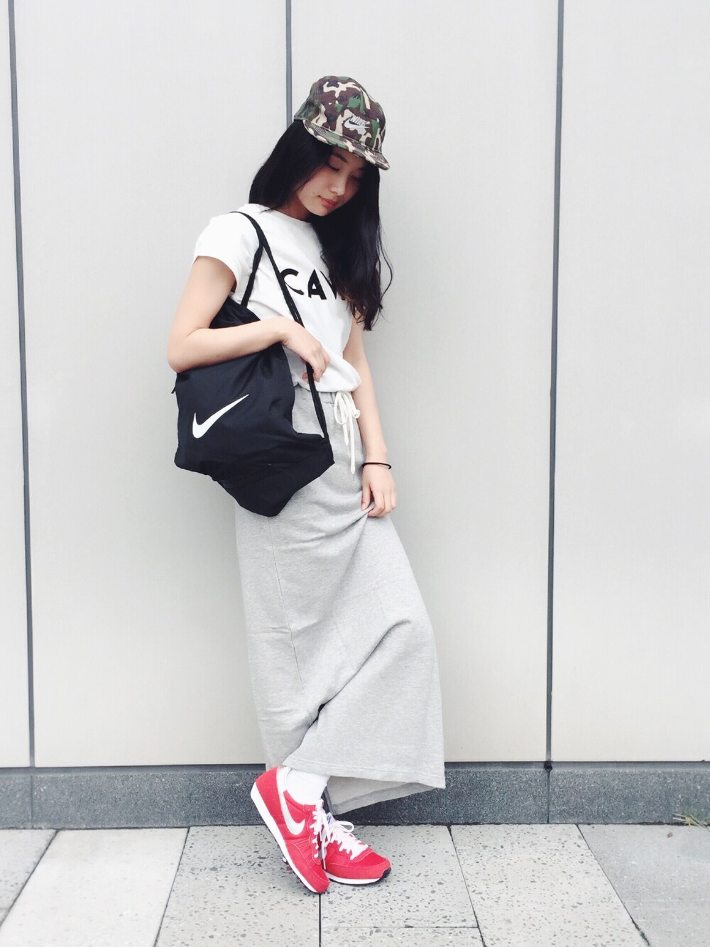 ホワイト系のTシャツ/カットソー、ブラック系のバックパック/リュック、グレー系のスカートを着用したレディースの春コーディネートの1枚目の写真