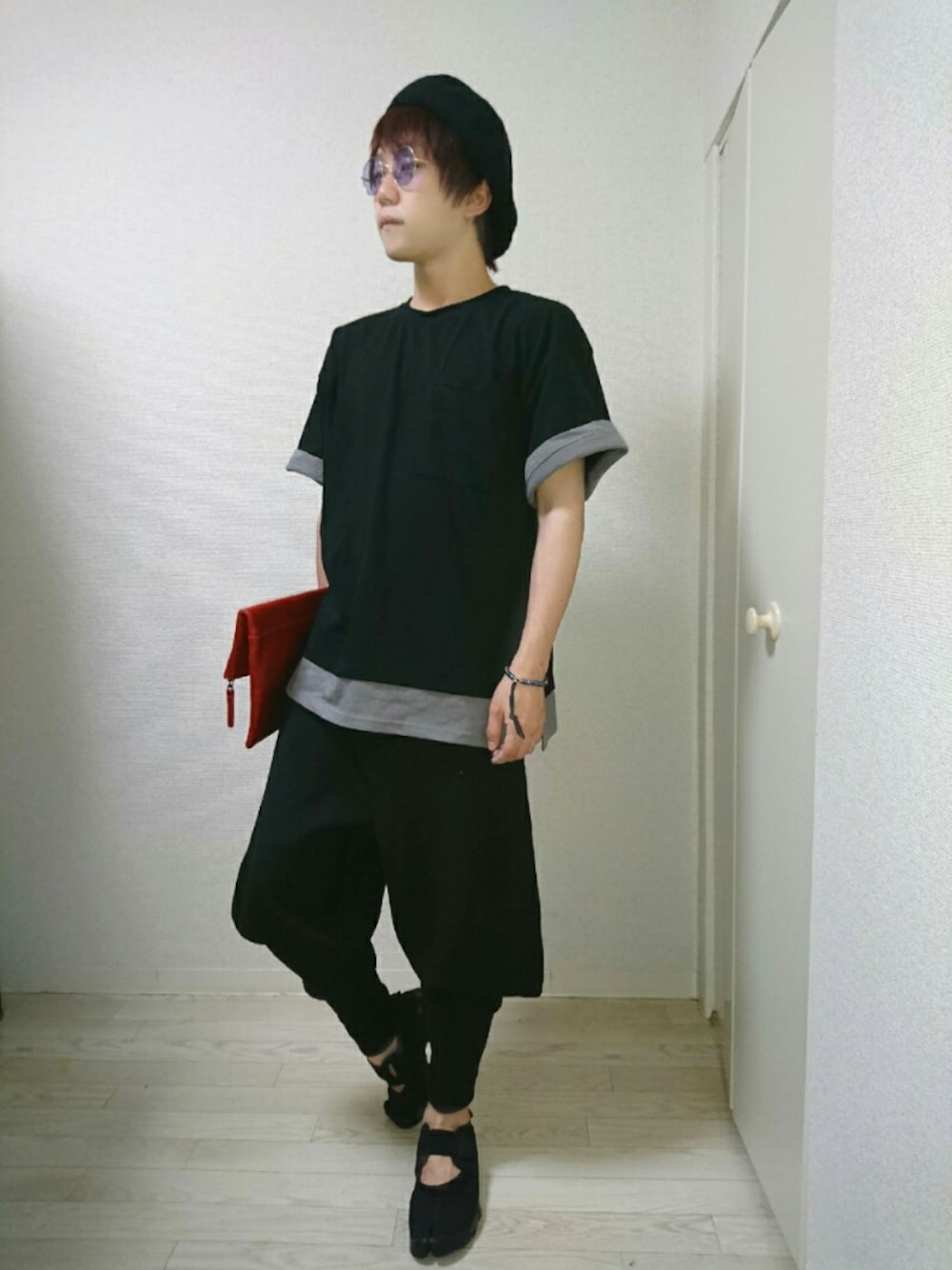 ブラック系のTシャツ/カットソー、ブラック系のその他パンツ、レッド系のクラッチバッグを着用したメンズの夏コーディネートの1枚目の写真