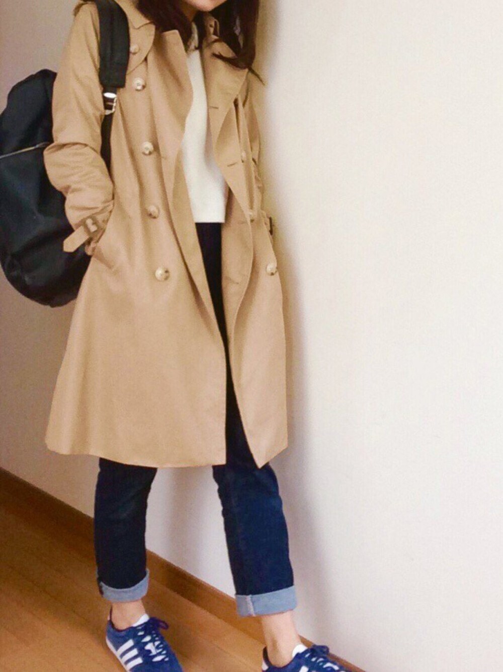 ブルー系のデニムパンツ、ベージュ系のトレンチコート、ホワイト系のニット/セーターを着用したレディースの秋コーディネートの1枚目の写真