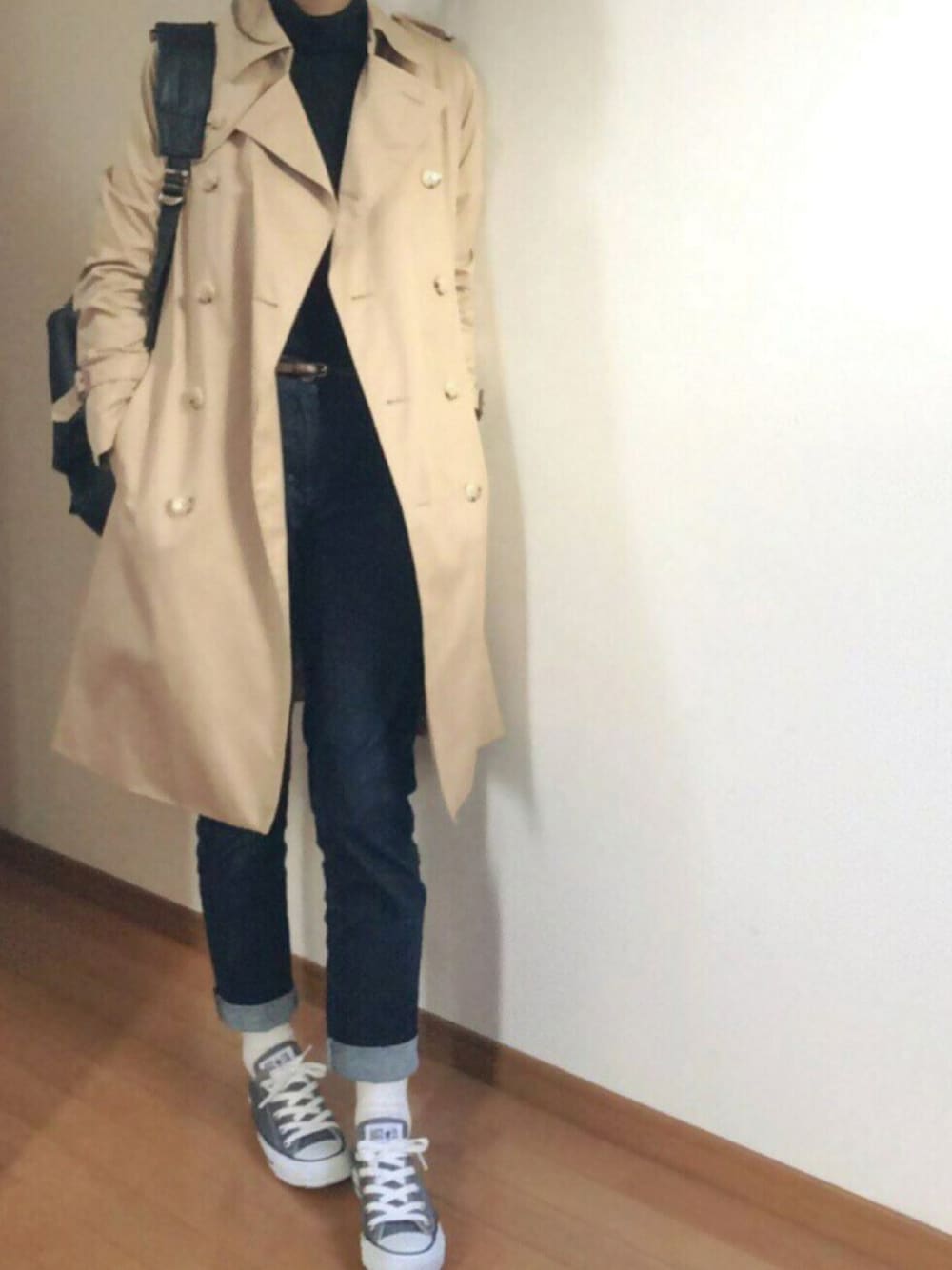 ベージュ系のトレンチコート、ブルー系のデニムパンツ、ブラック系のバックパック/リュックを着用したレディースの秋コーディネートの1枚目の写真