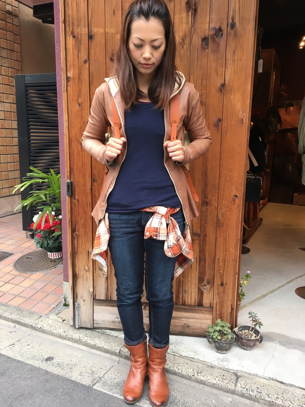 ブラウン系のブルゾン、オレンジ系のシャツ/ブラウス、ブルー系のデニムパンツを着用したレディースの秋コーディネートの1枚目の写真