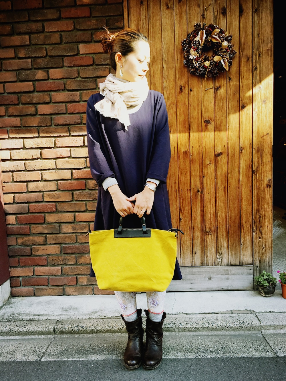 ブルー系のワンピース、イエロー系のトートバッグ、ブラウン系のブーツを着用したレディースの冬コーディネートの1枚目の写真