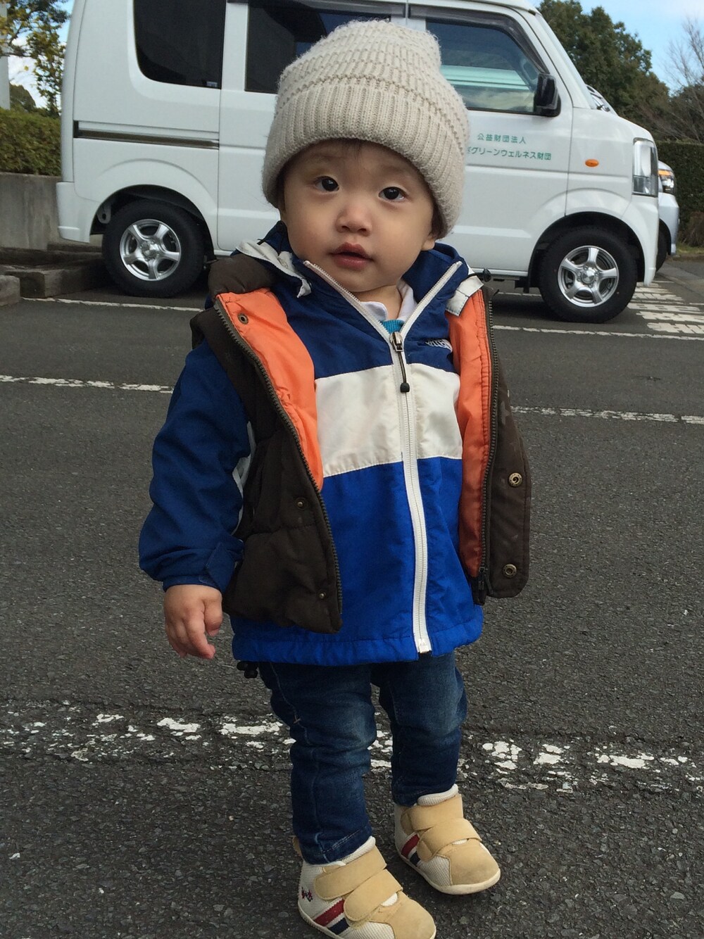 ブルー系のマウンテンパーカー、グリーン系のダウンベスト、ブルー系のデニムパンツを着用したキッズの春コーディネートの1枚目の写真