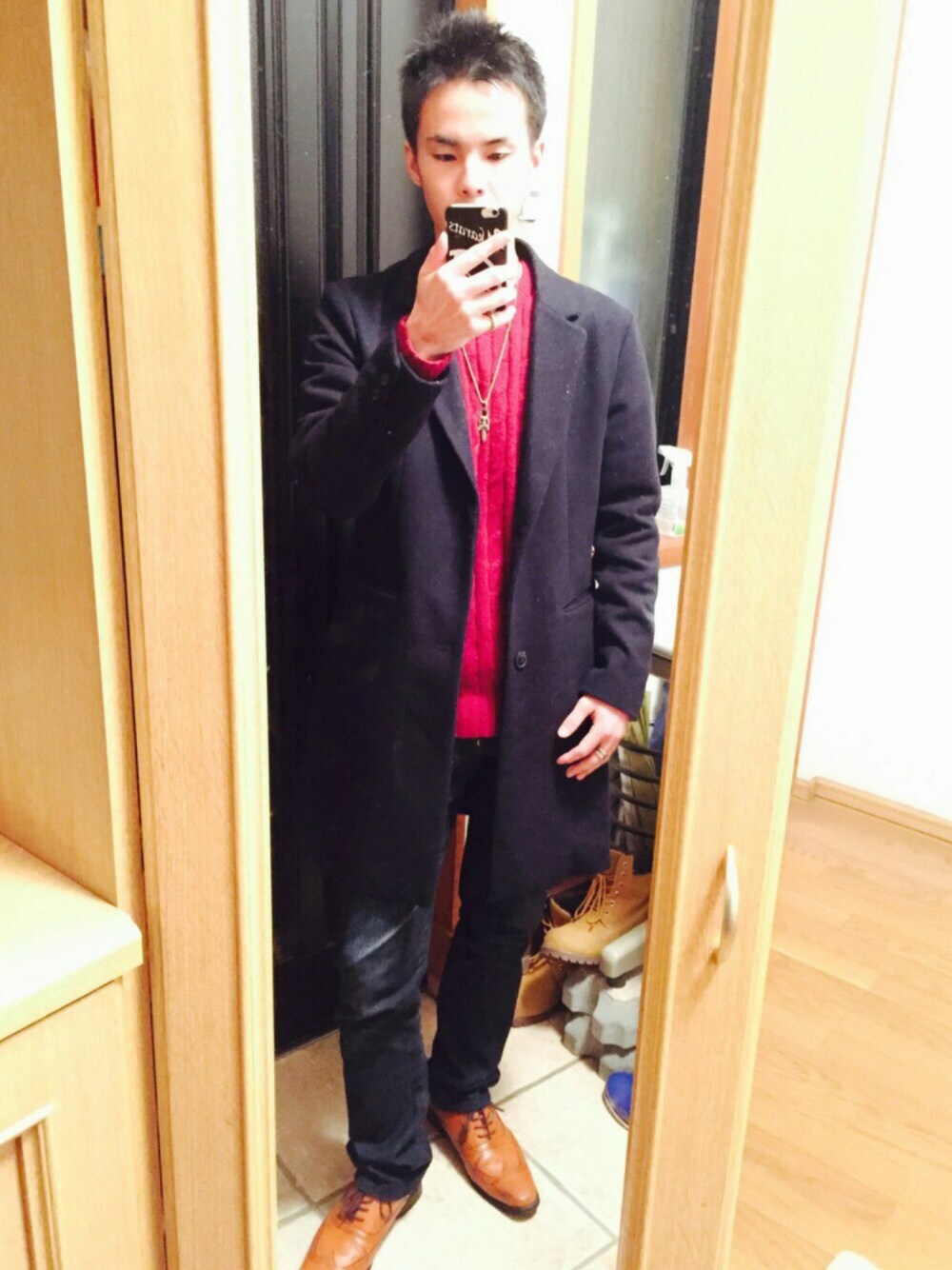 ブルー系のチェスターコート、レッド系のニット/セーター、ブルー系のデニムパンツを着用したメンズの冬コーディネートの1枚目の写真