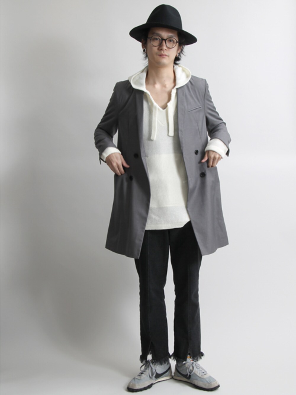 グレー系のチェスターコート、ホワイト系のニット/セーター、ブラック系のデニムパンツを着用したメンズの秋コーディネートの1枚目の写真