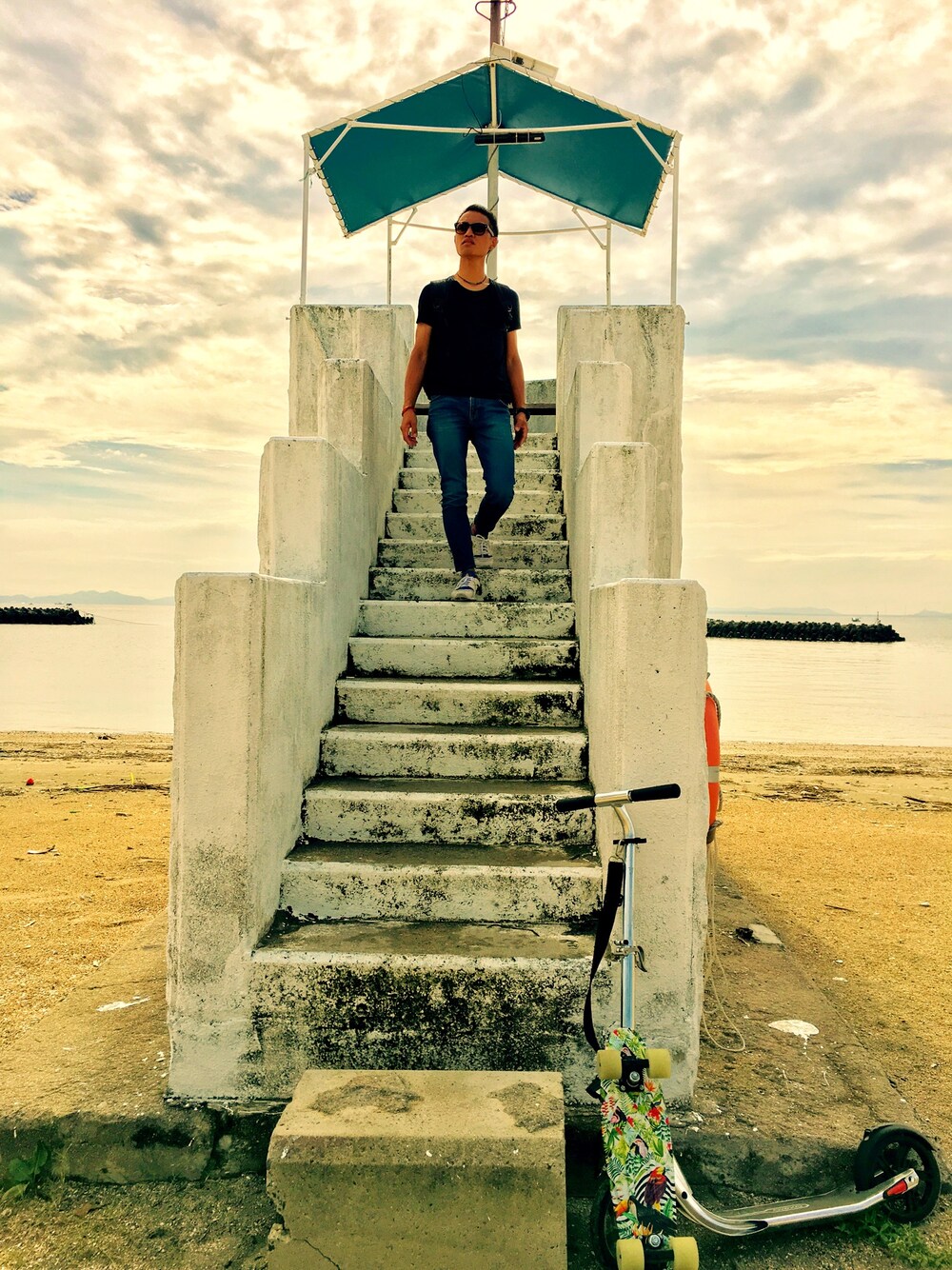 ブルー系のデニムパンツ、ホワイト系のスニーカー、ブラック系のTシャツ/カットソーを着用したメンズの秋コーディネートの1枚目の写真