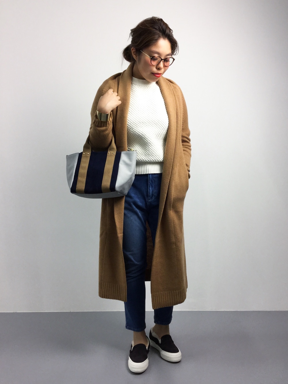 イエロー系のカーディガン/ボレロ、ホワイト系のニット/セーター、ブルー系のトートバッグを着用したレディースの夏コーディネートの1枚目の写真