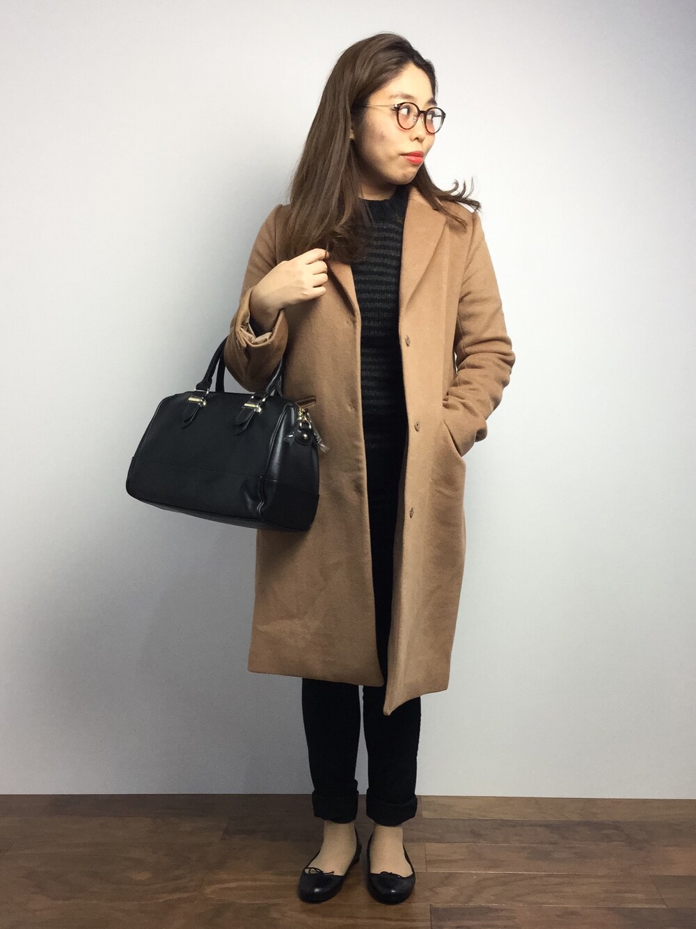 ブラック系のニット/セーター、イエロー系のチェスターコート、ブラック系のボストンバッグを着用したレディースの秋コーディネートの1枚目の写真