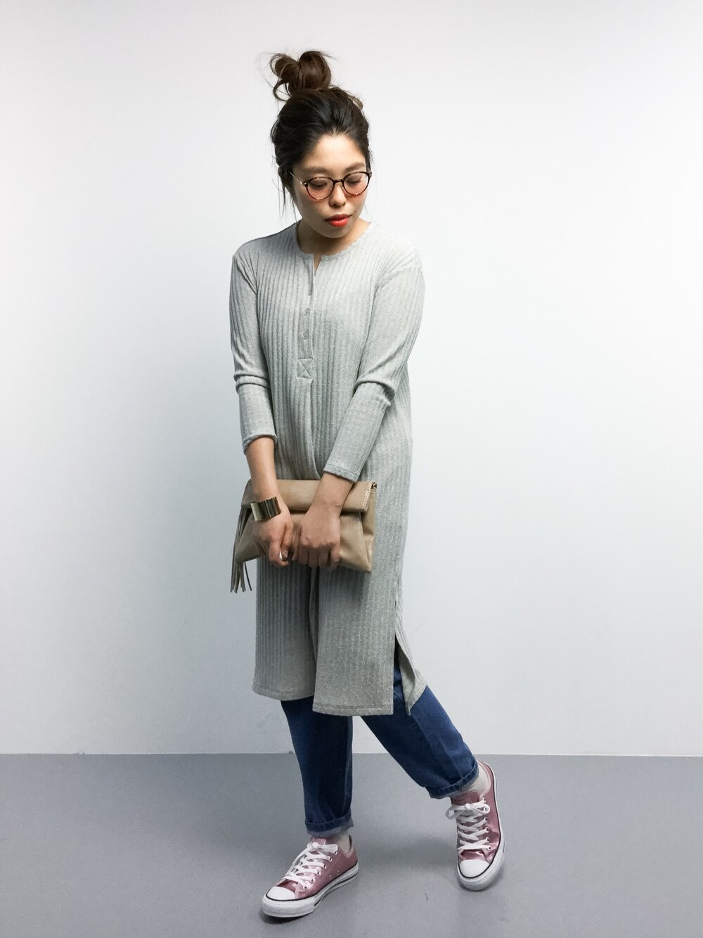 ベージュ系のクラッチバッグ、ブルー系のデニムパンツ、ゴールド系のスニーカーを着用したレディースの冬コーディネートの1枚目の写真