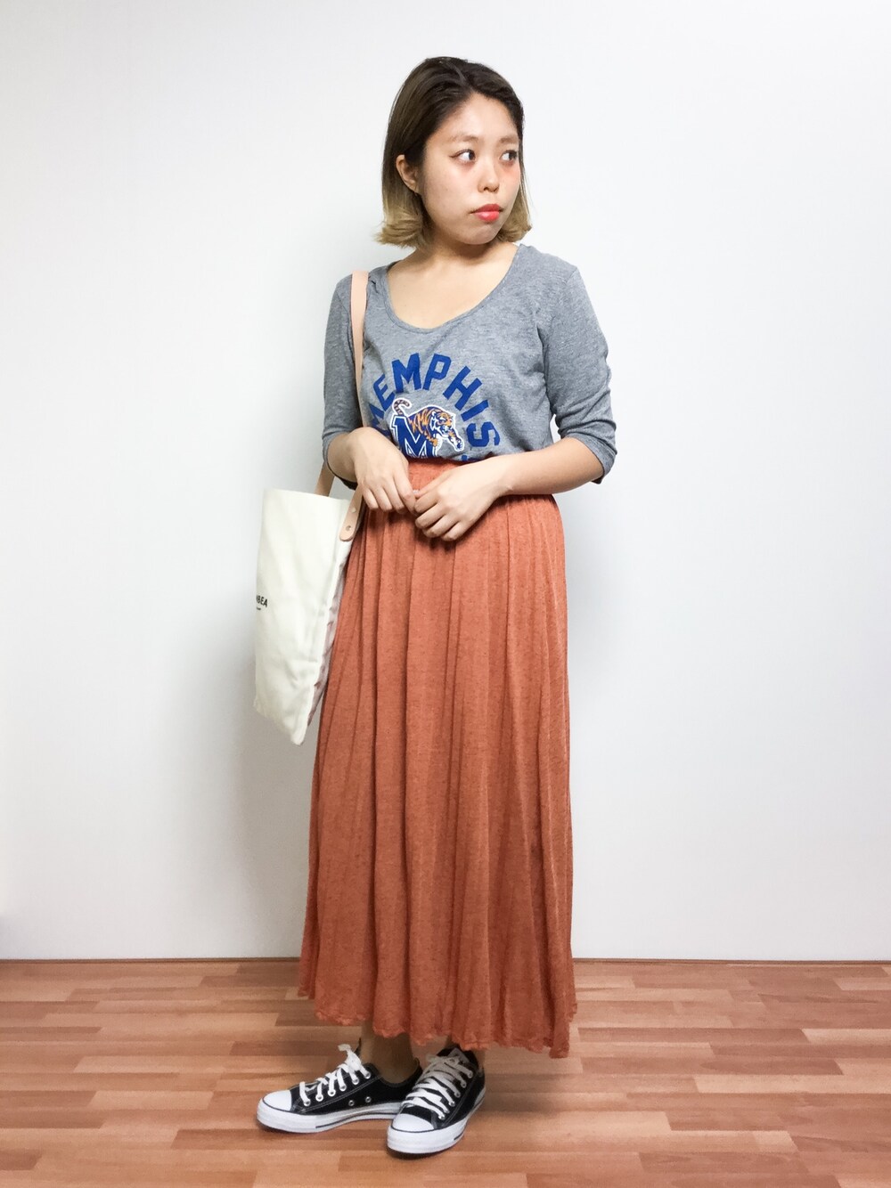 ホワイト系のトートバッグ、グレー系のTシャツ/カットソー、オレンジ系のスカートを着用したレディースの夏コーディネートの1枚目の写真