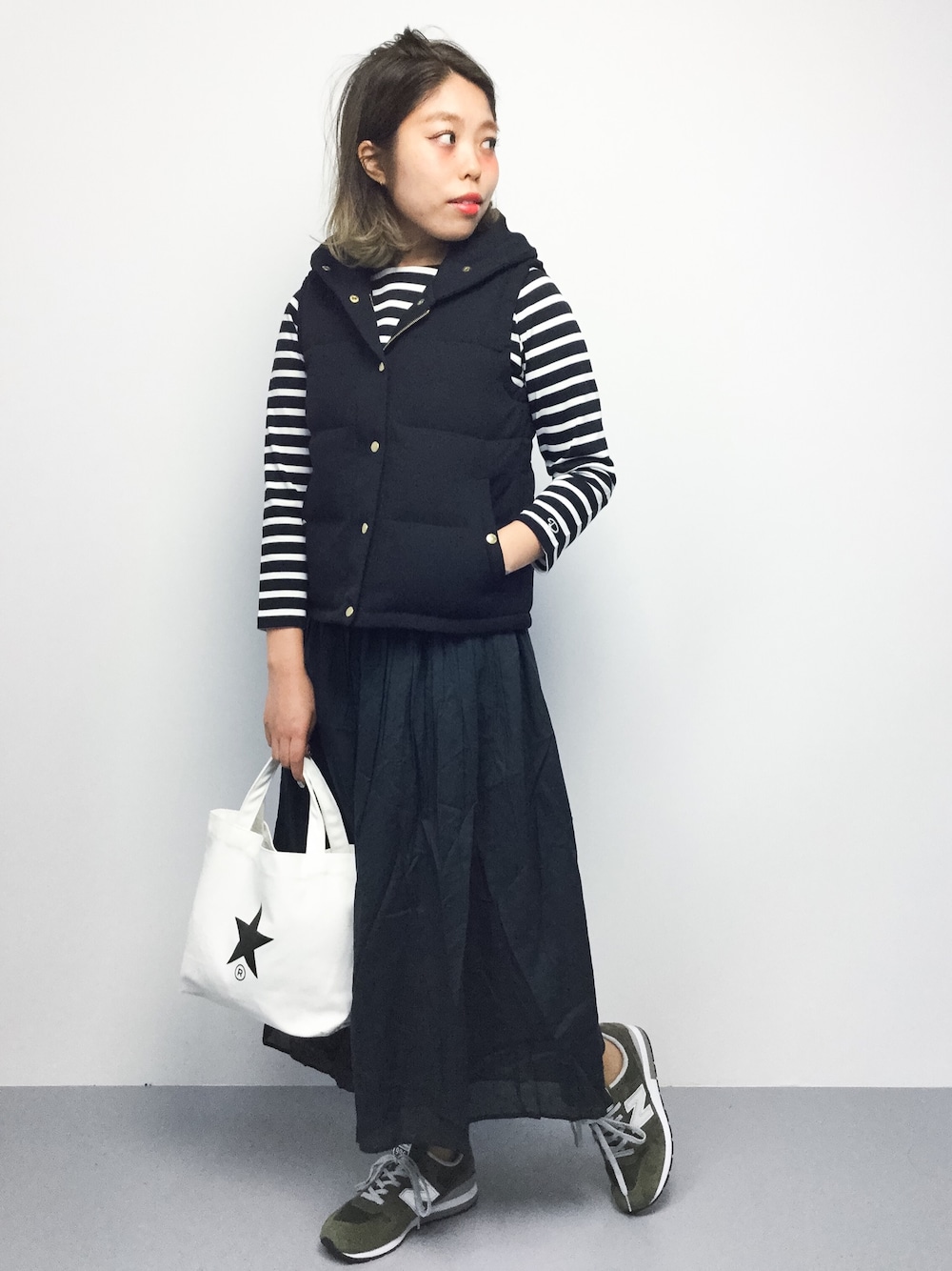 ブラック系のTシャツ/カットソー、ブラック系のダウンベスト、ホワイト系のトートバッグを着用したレディースの秋コーディネートの1枚目の写真