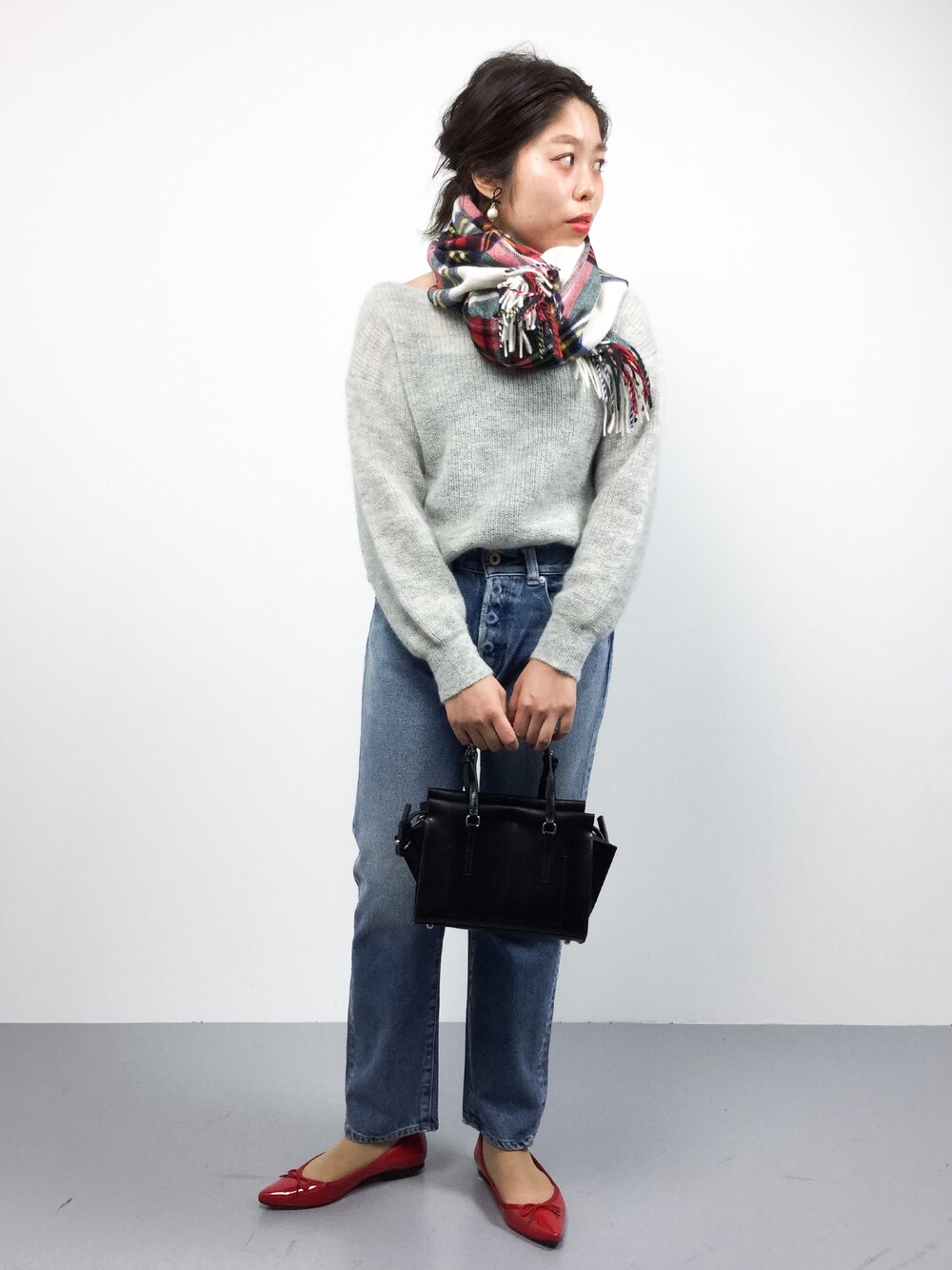 グレー系のニット/セーター、ブルー系のデニムパンツ、ブラック系のショルダーバッグを着用したレディースの秋コーディネートの1枚目の写真