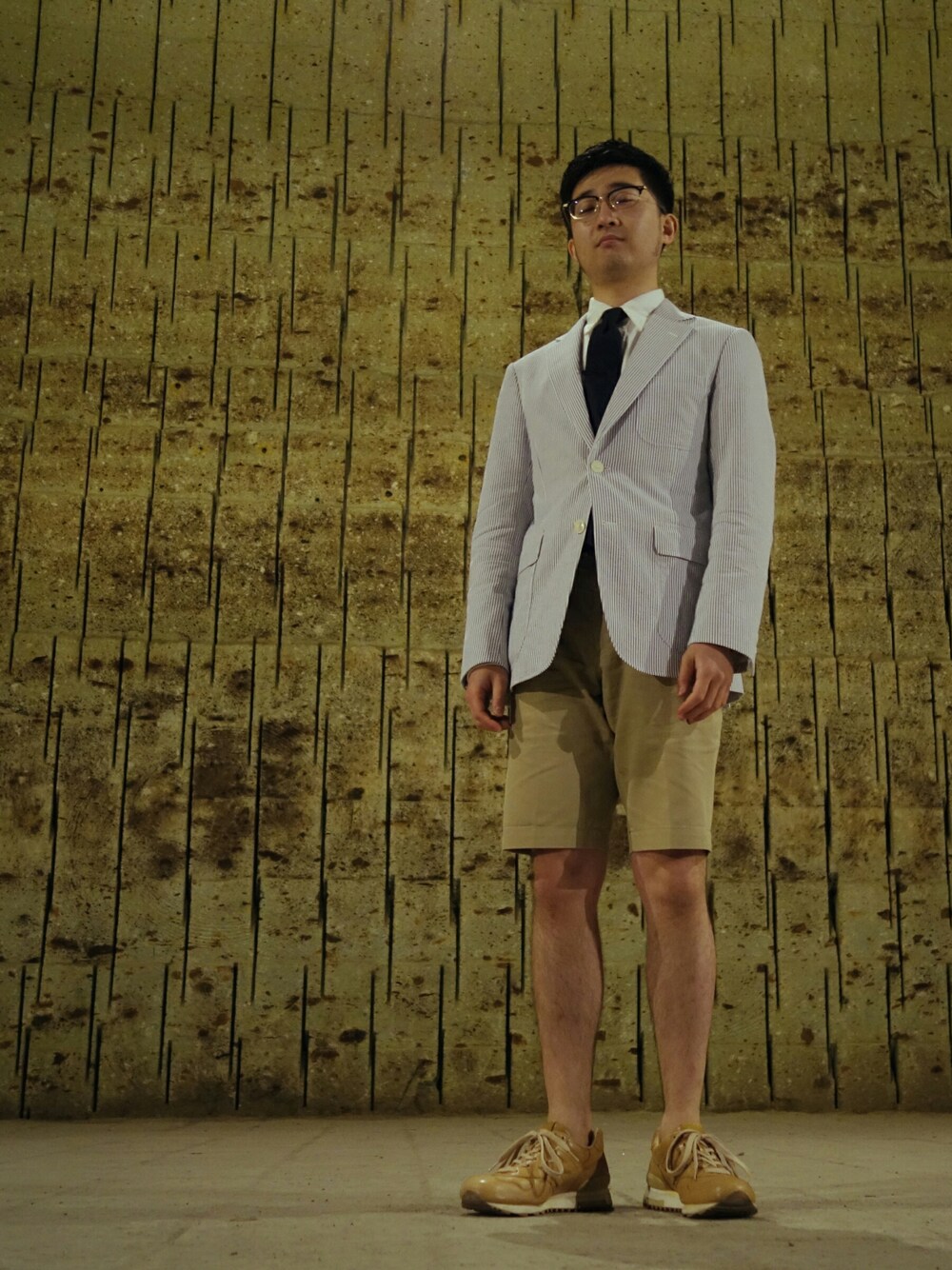 ホワイト系のスーツジャケット、ブルー系のネクタイ、ブラウン系のスニーカーを着用したメンズの秋コーディネートの1枚目の写真