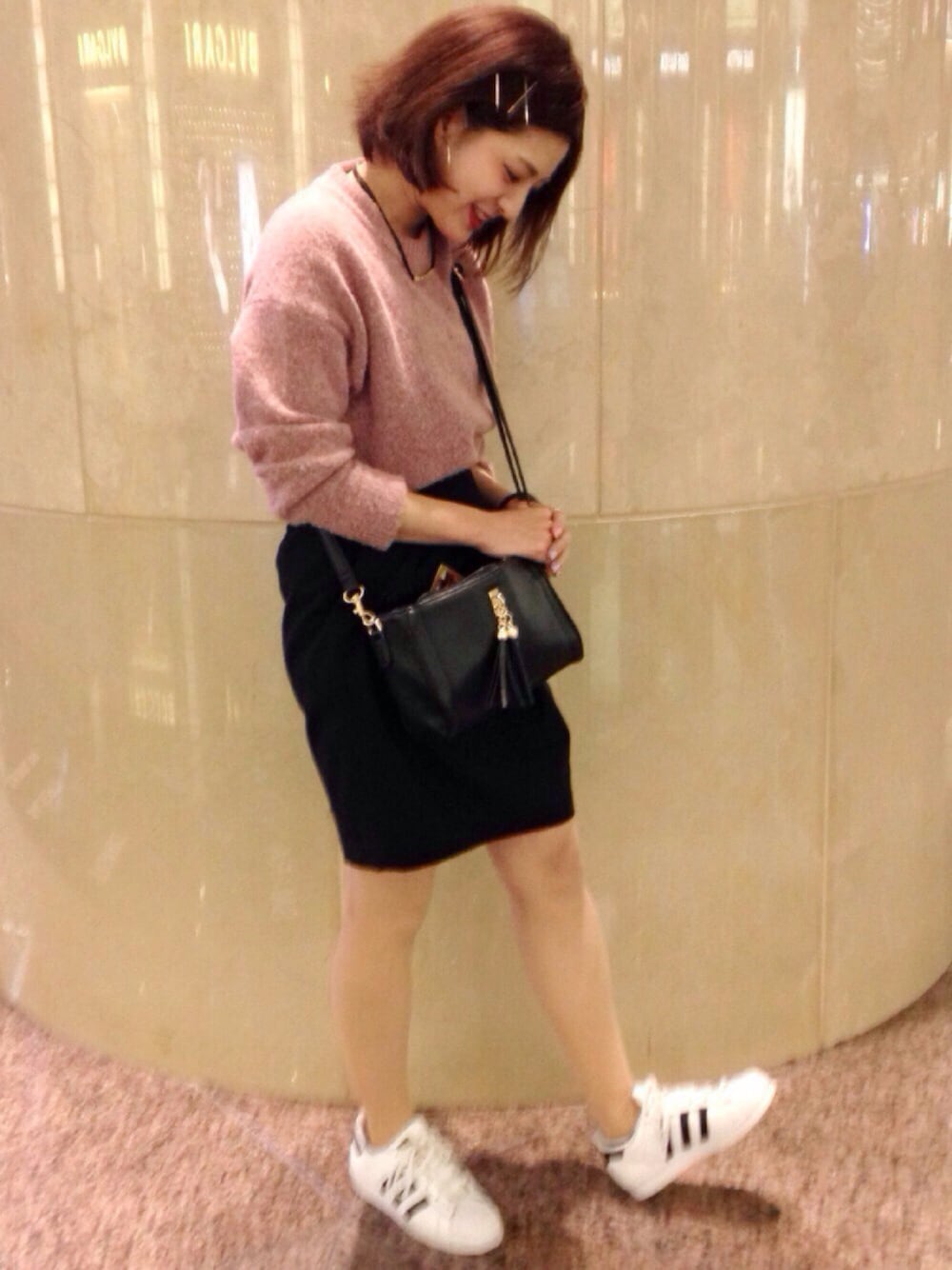 ピンク系のニット/セーター、ブラック系のバッグ、ホワイト系のスニーカーを着用したレディースの春コーディネートの1枚目の写真
