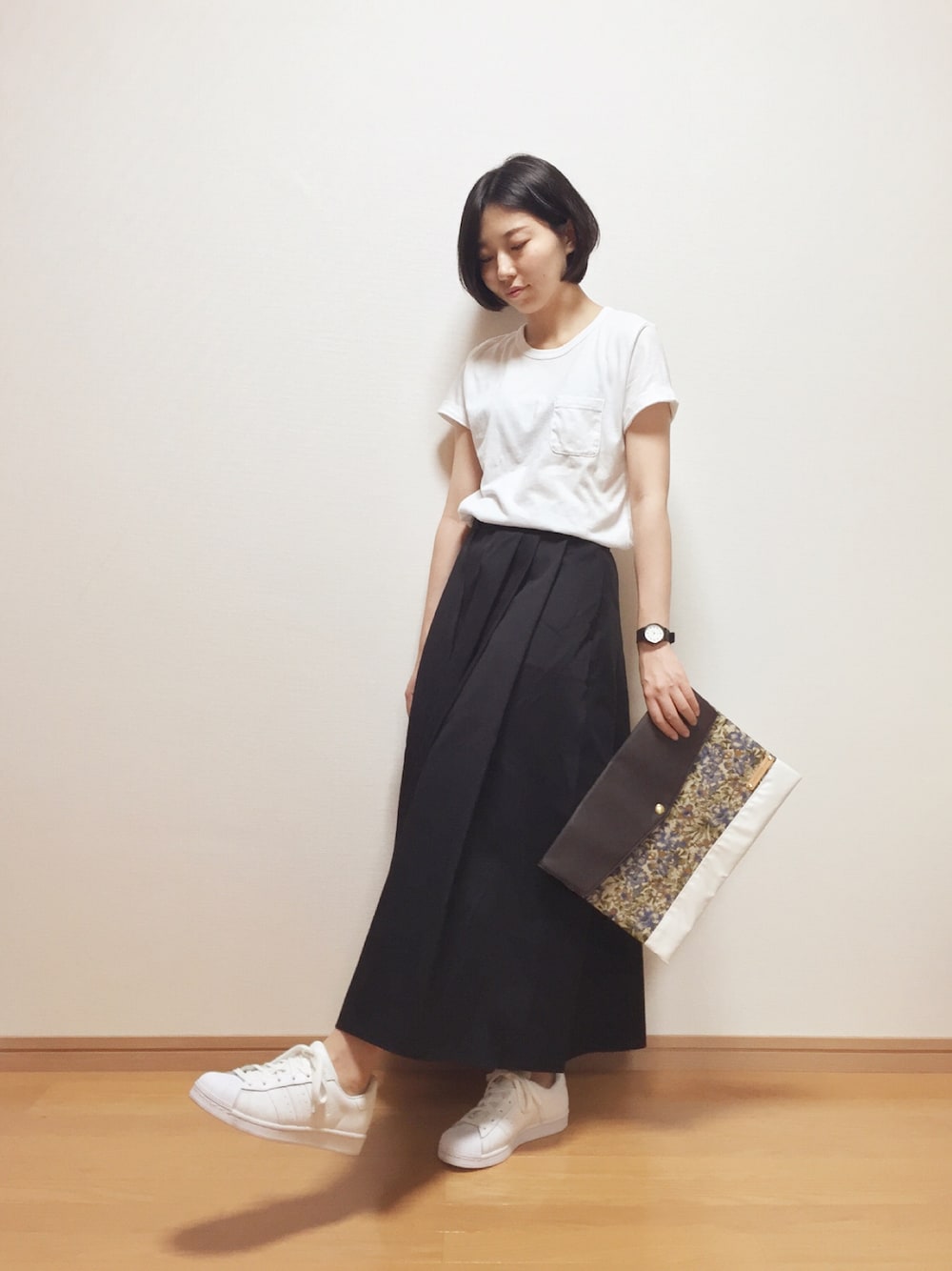 ホワイト系のTシャツ/カットソー、ブラック系のスカート、ホワイト系のスニーカーを着用したレディースの秋コーディネートの1枚目の写真