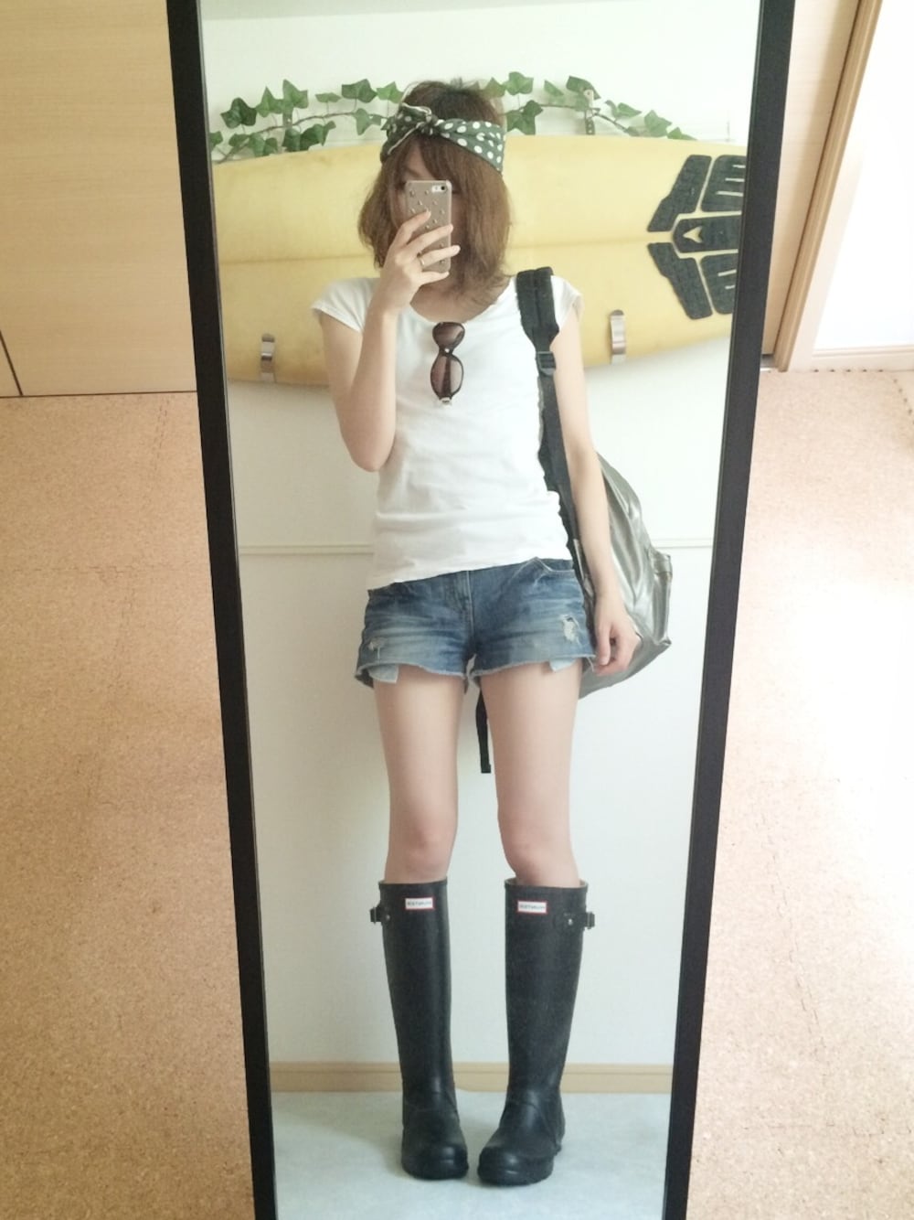 ブルー系のデニムパンツ、ブラック系のレインシューズ、シルバー系のバックパック/リュックを着用したレディースの夏コーディネートの1枚目の写真