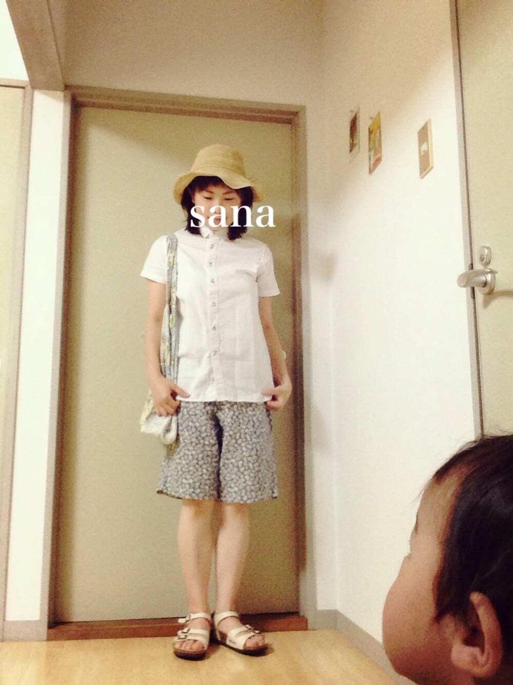 ブルー系のトートバッグ、ホワイト系のシャツ/ブラウス、ベージュ系のサンダルを着用したレディースの夏コーディネートの1枚目の写真