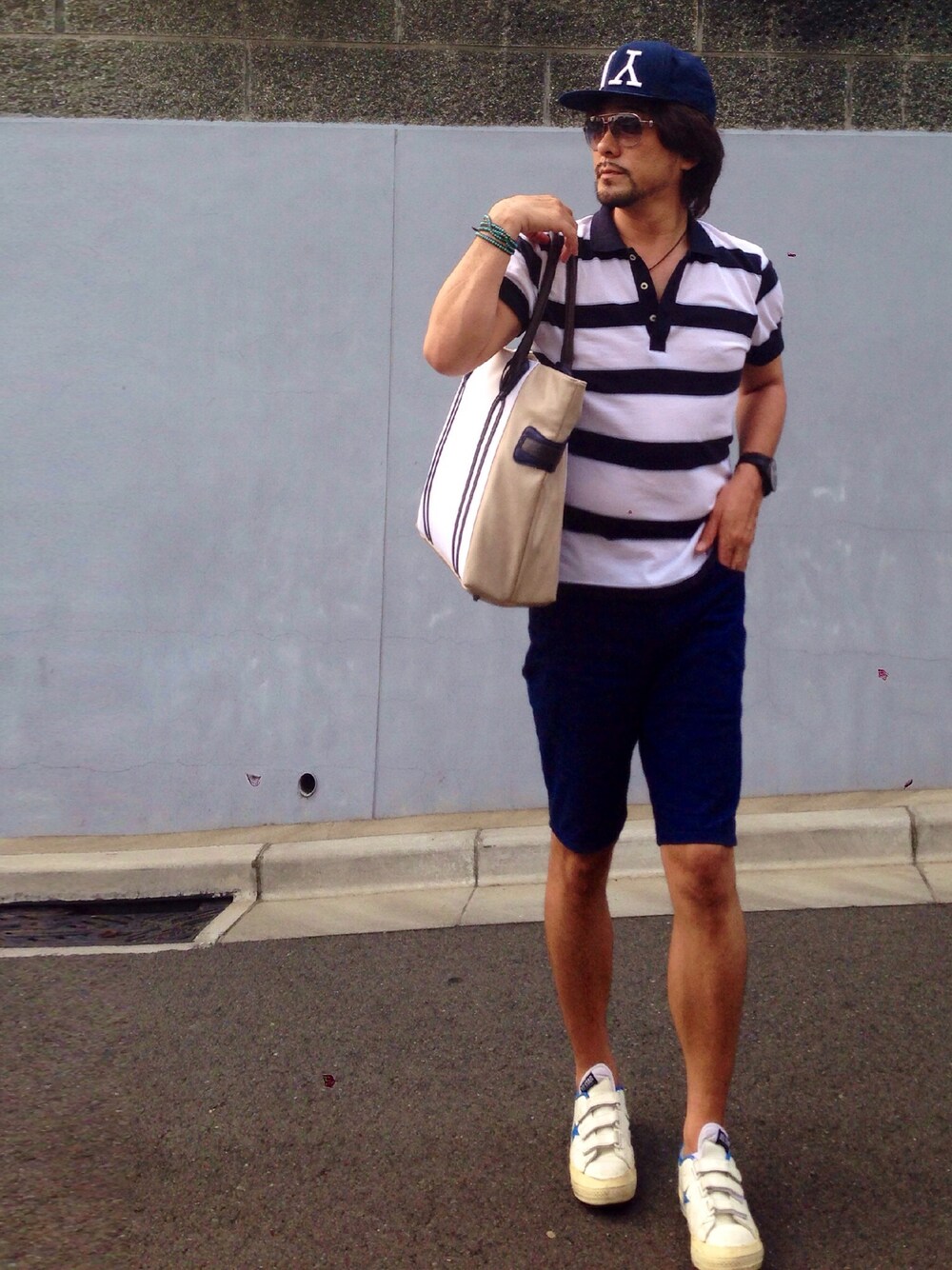 ブルー系のポロシャツ、ブルー系のスラックス、ホワイト系のスニーカーを着用したメンズの夏コーディネートの1枚目の写真