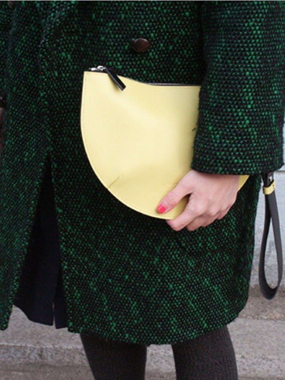 オレンジ系のクラッチバッグを着用したレディースの冬コーディネートの1枚目の写真