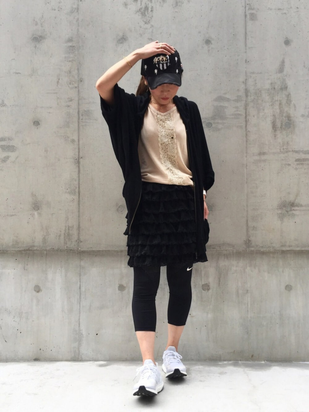 ホワイト系のスニーカー、ブラック系のパーカー、ブラック系のスカートを着用したレディースの秋コーディネートの1枚目の写真