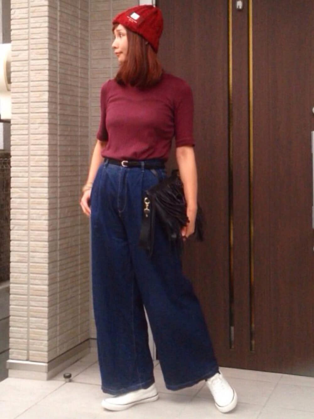 レッド系のTシャツ/カットソー、ブルー系のデニムパンツ、ブラック系のショルダーバッグを着用したレディースの秋コーディネートの1枚目の写真