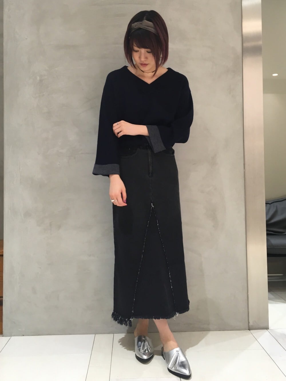 ブラック系のデニムスカート、シルバー系のシューズ、グレー系のヘアバンドを着用したレディースの秋コーディネートの1枚目の写真